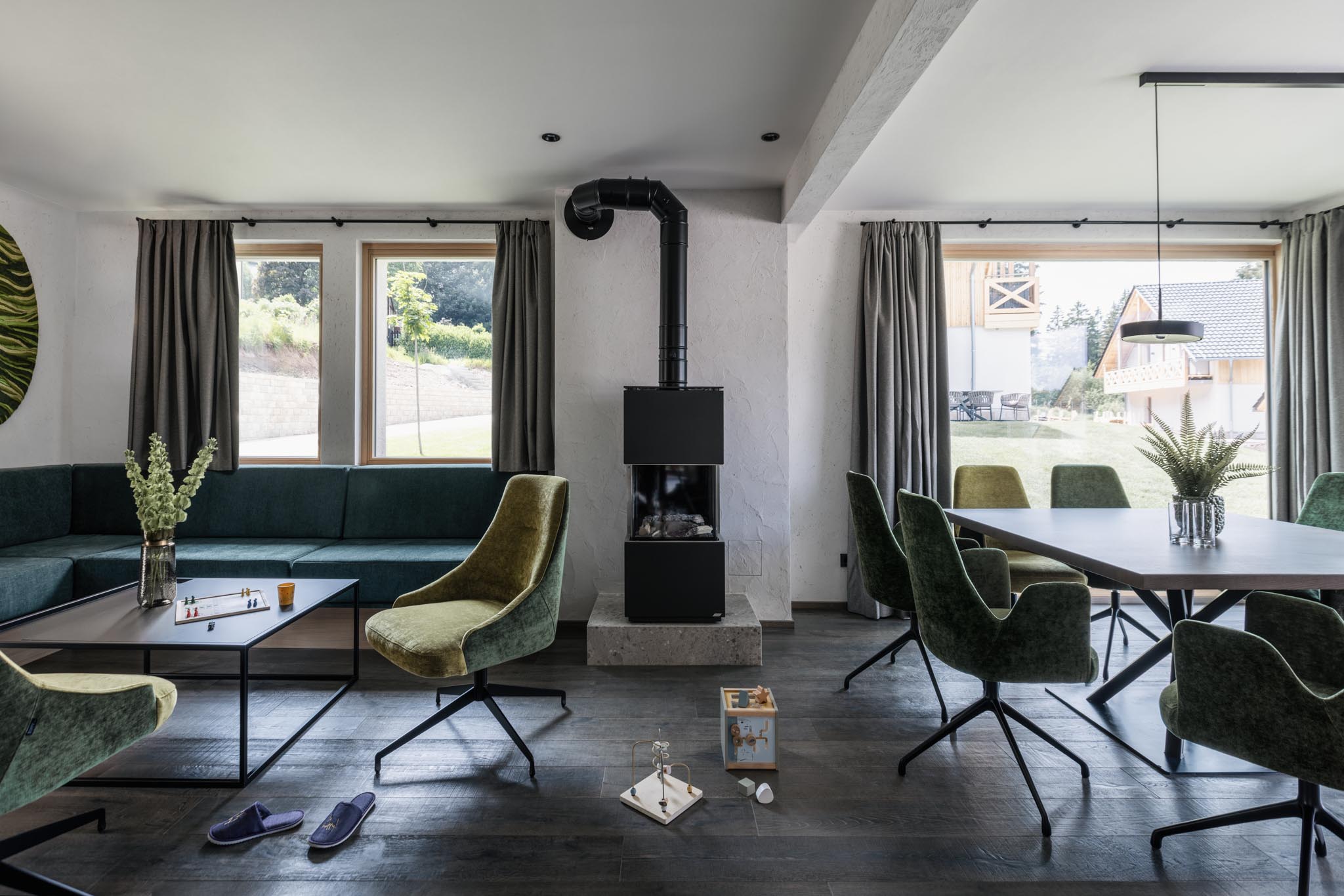 Living room with sofa, fireplace and dining area with dining table and chairs in the chalet at The Grand Green – Familux Resort.
