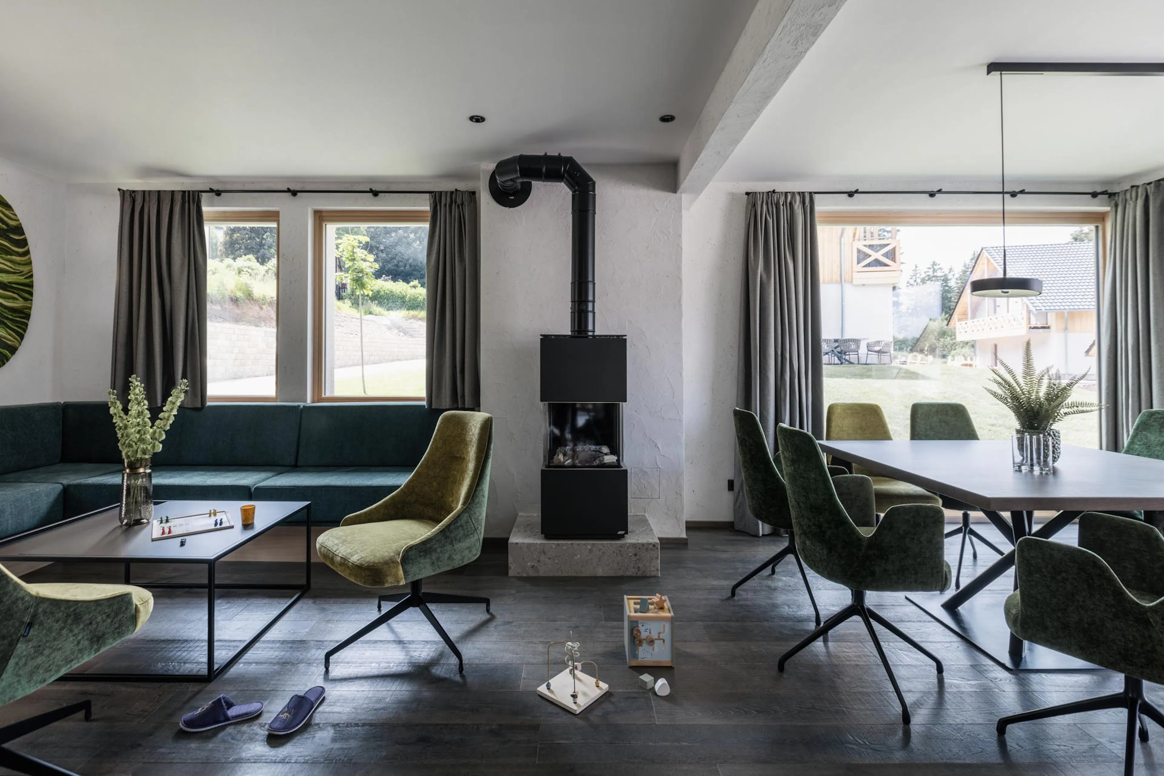 Living room with sofa, fireplace and dining area with dining table and chairs in the chalet at The Grand Green – Familux Resort.