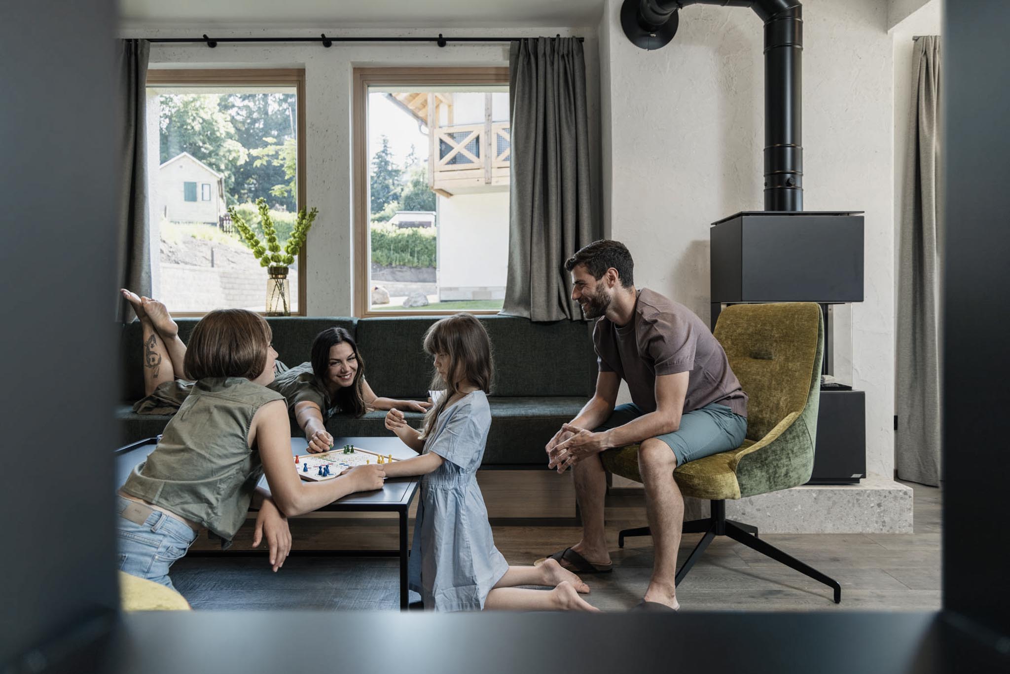 Family playing a board game in the living room of the chalet at The Grand Green – Familux Resort.