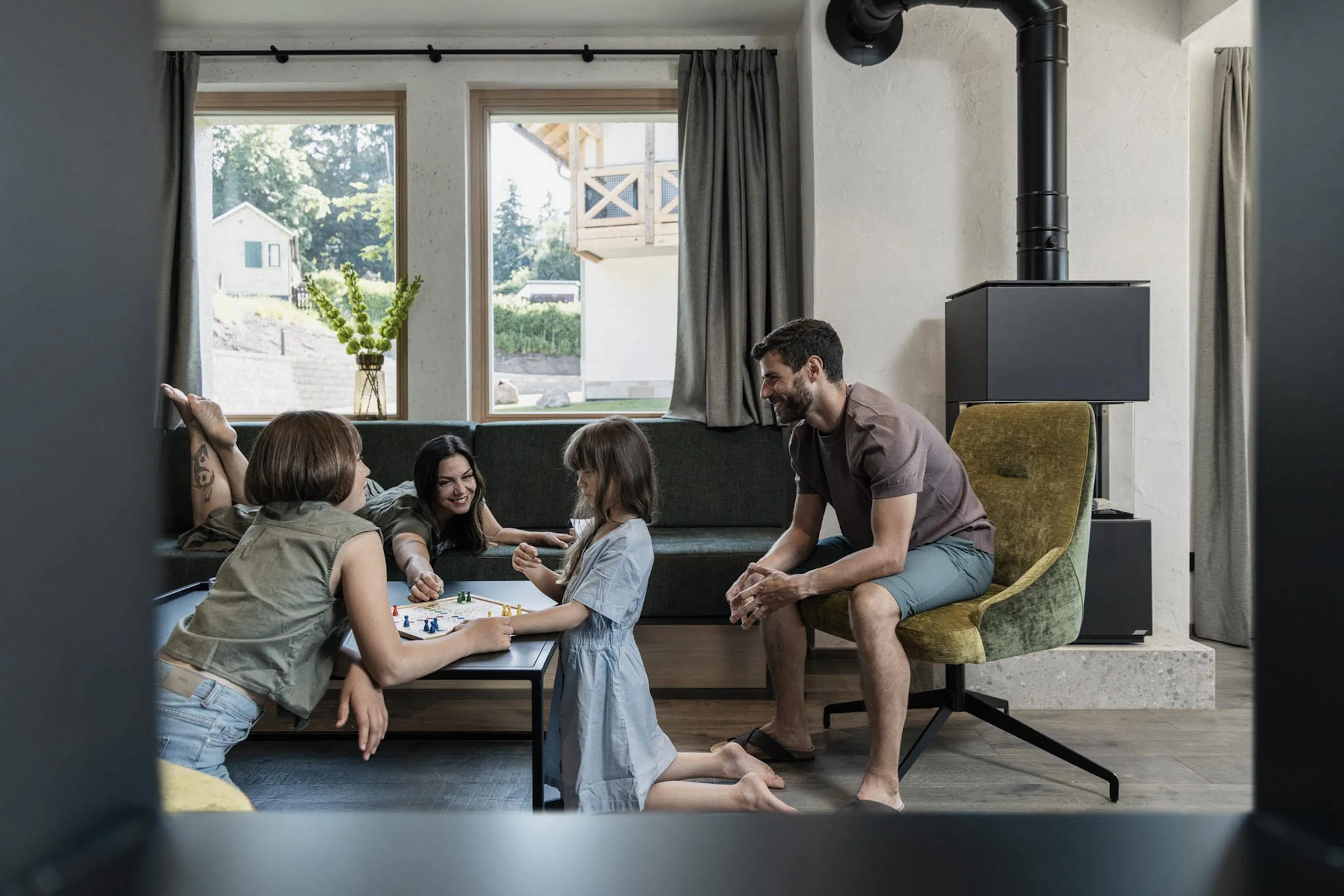 Familie spielt im Wohnzimmer des Chalets ein Brettspiel im The Grand Green - Familux Resort.