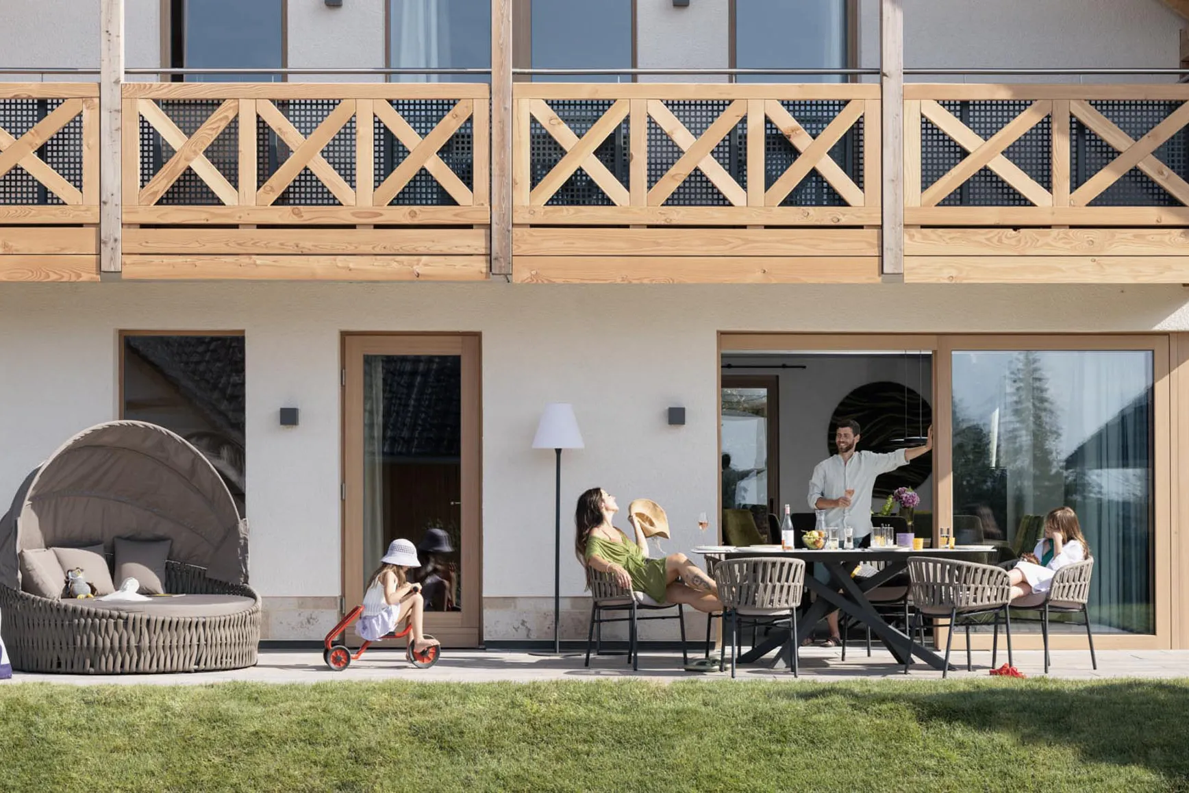 Family sitting on the terrace of a chalet at The Grand Green – Familux Resort.