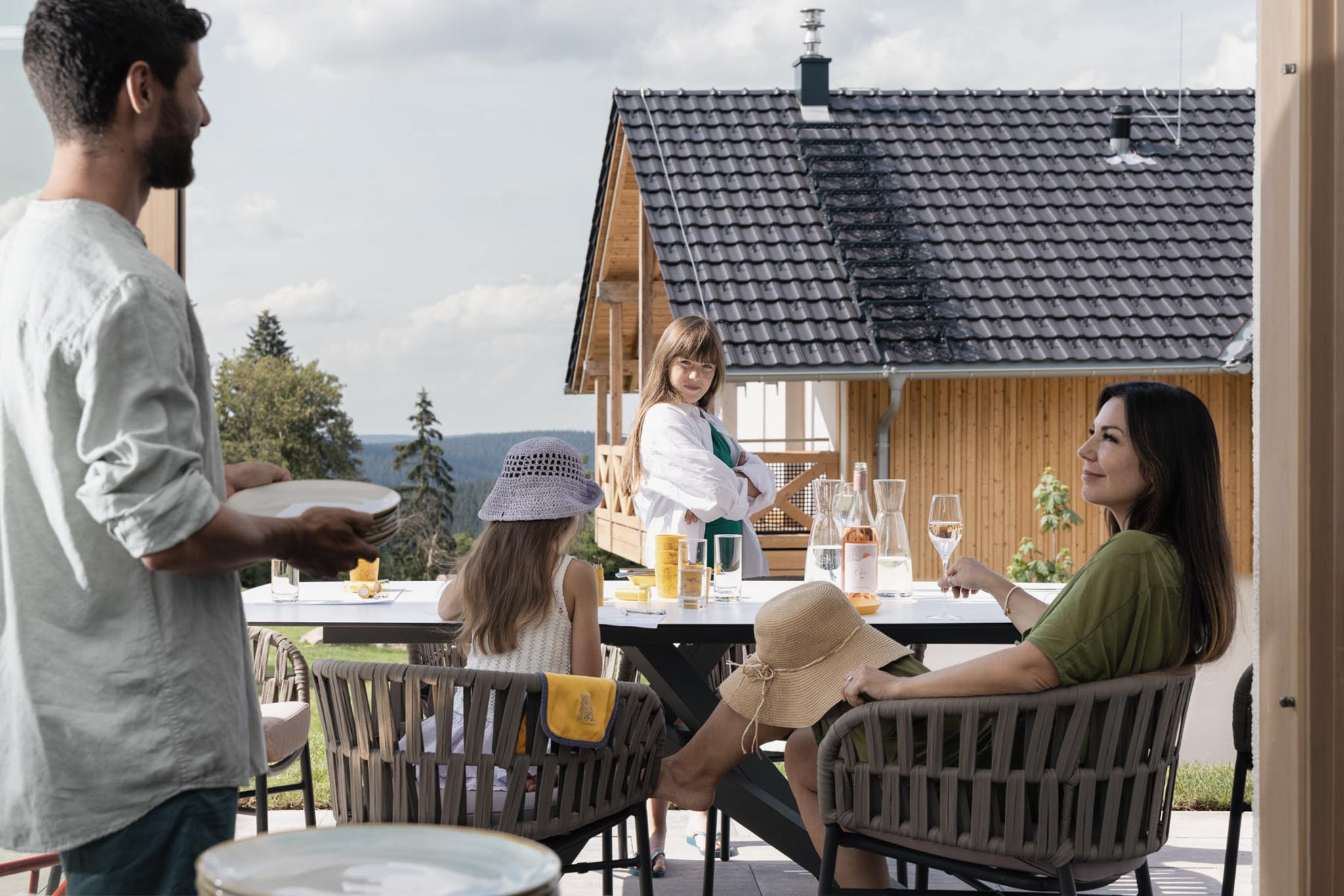 Family eating and drinking at a table on the terrace of a chalet at The Grand Green – Familux Resort.
