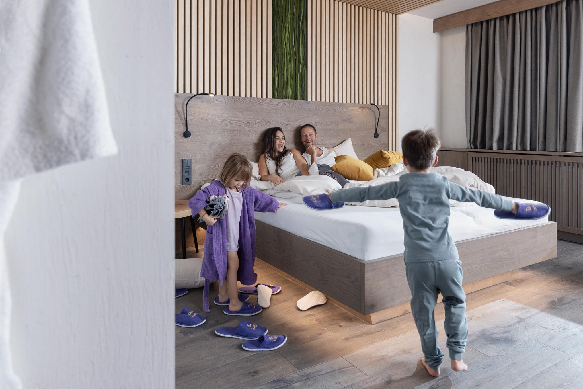 Family cuddling in bed in a family suite at The Grand Green – Familux Resort.