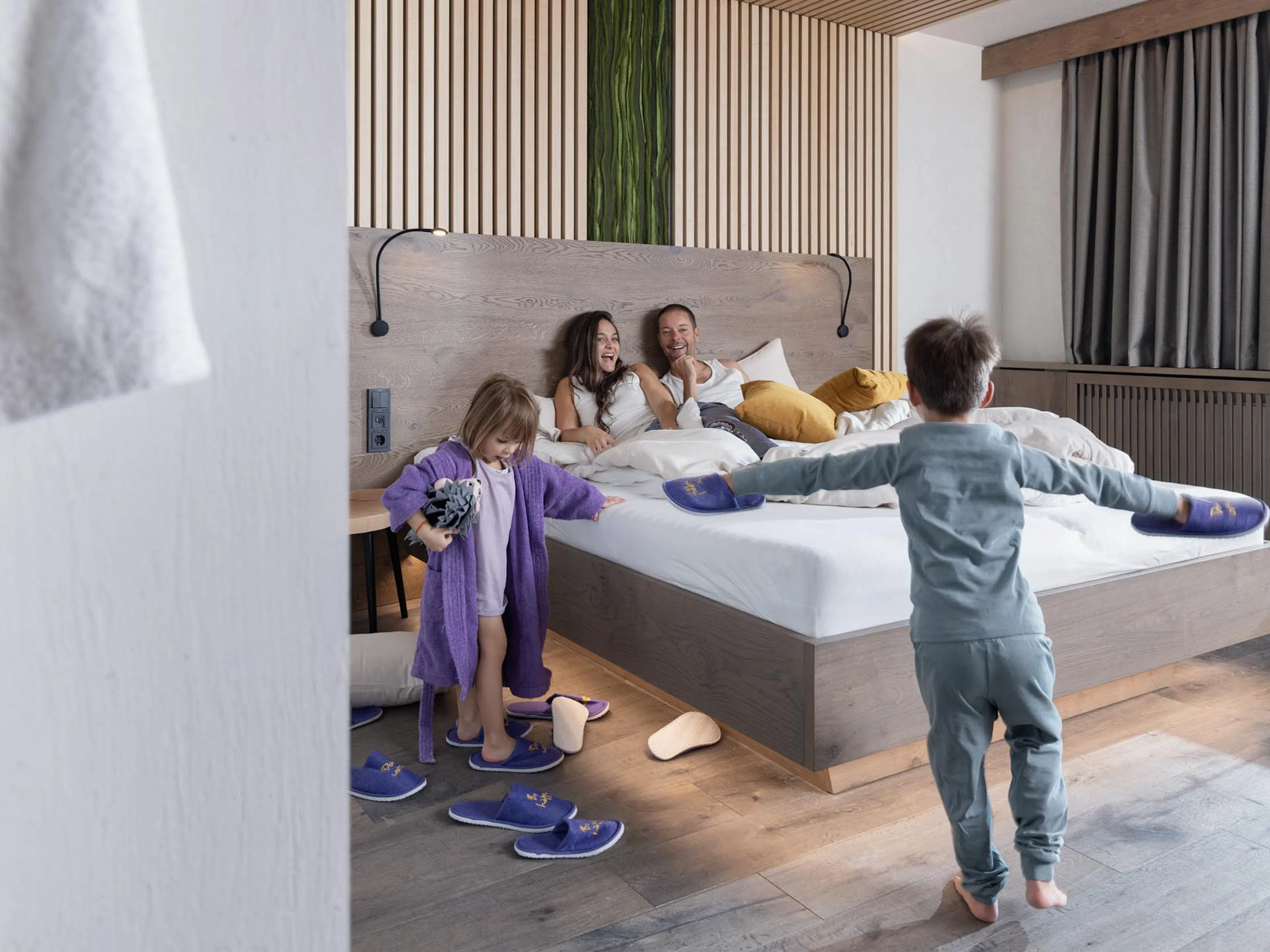 Family cuddling in bed in a family suite at The Grand Green – Familux Resort.