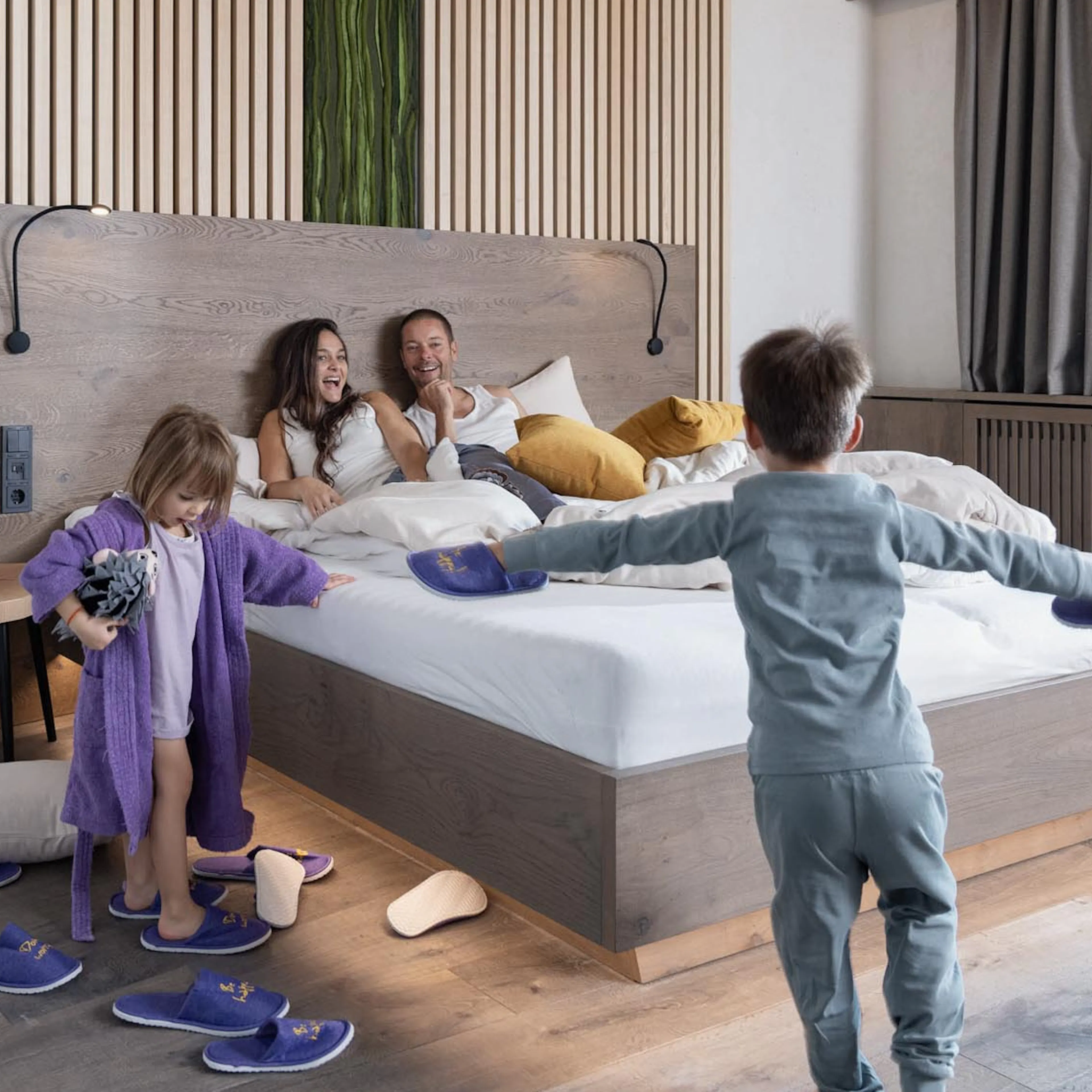 Family cuddling in bed in a family suite at The Grand Green – Familux Resort.