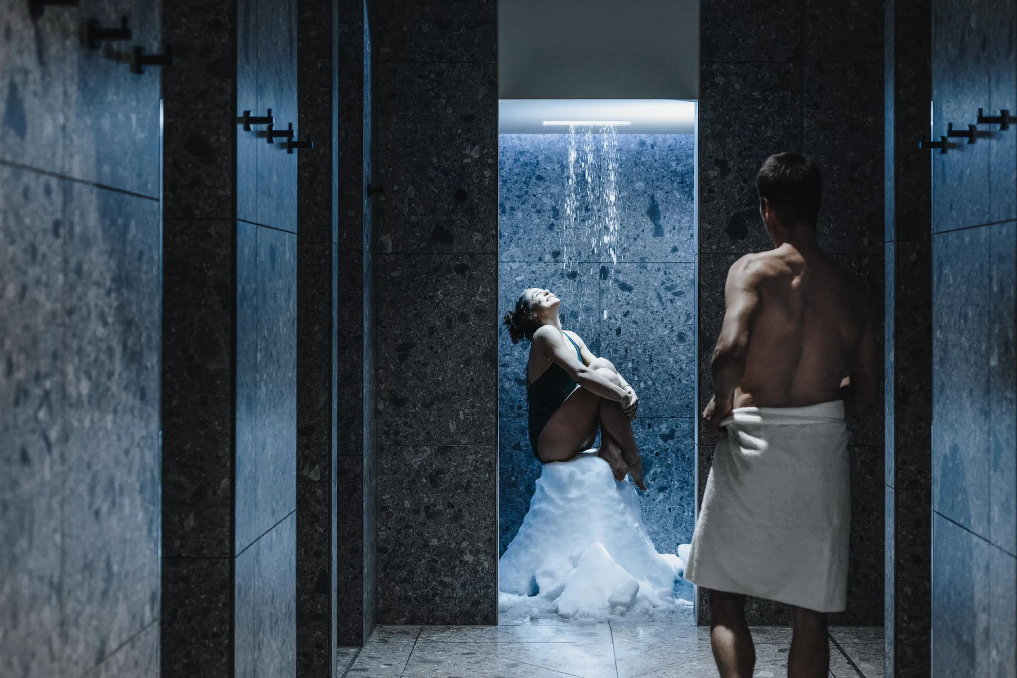 Eltern stehen im Schneebrunnen im Wellnessbereich des The Grand Green - Familux Resorts.