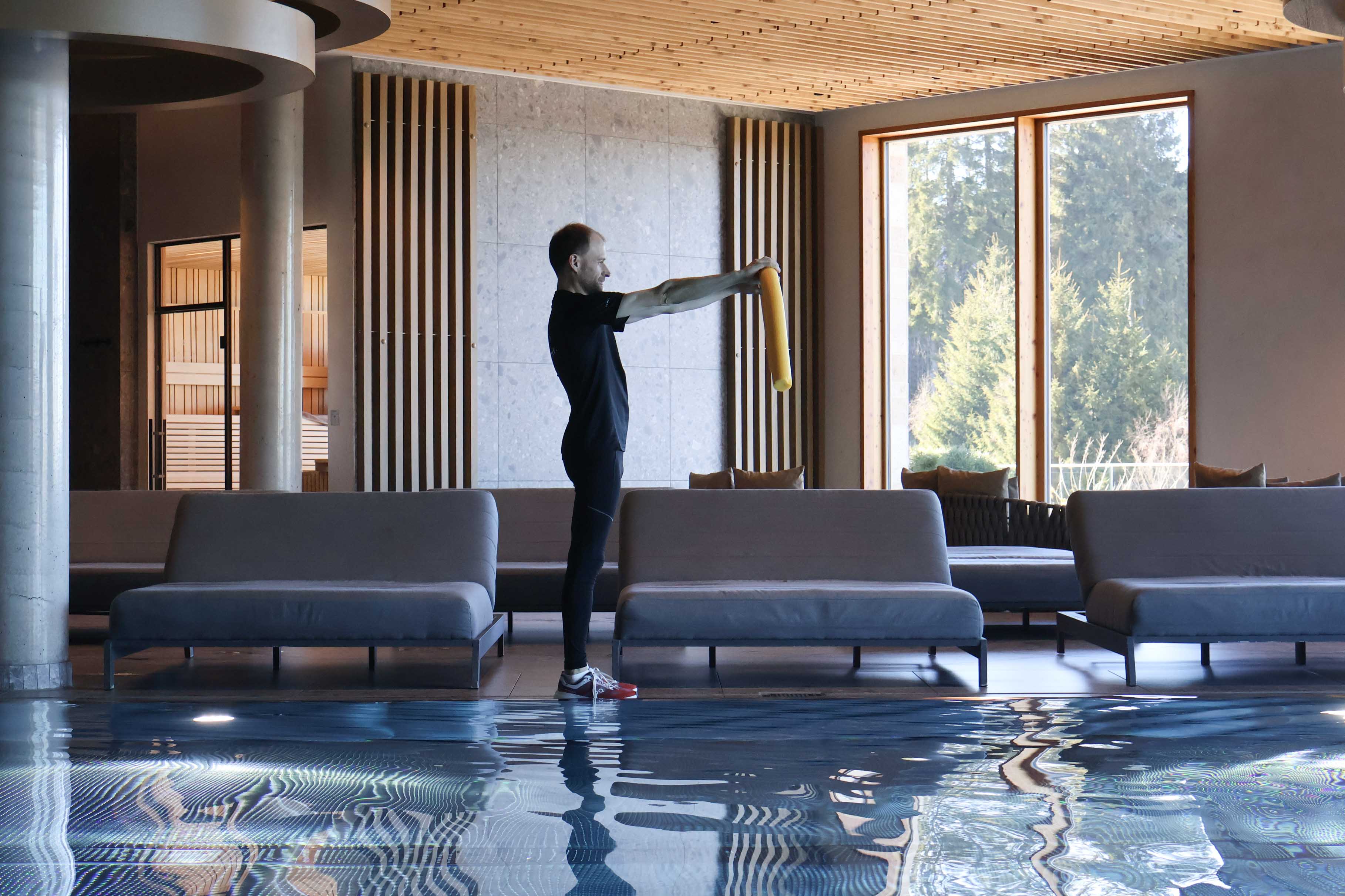 Mann zeigt Übungen zur Aqua Gymnastik im Pool des The Grand Green - Familux Resorts vor.