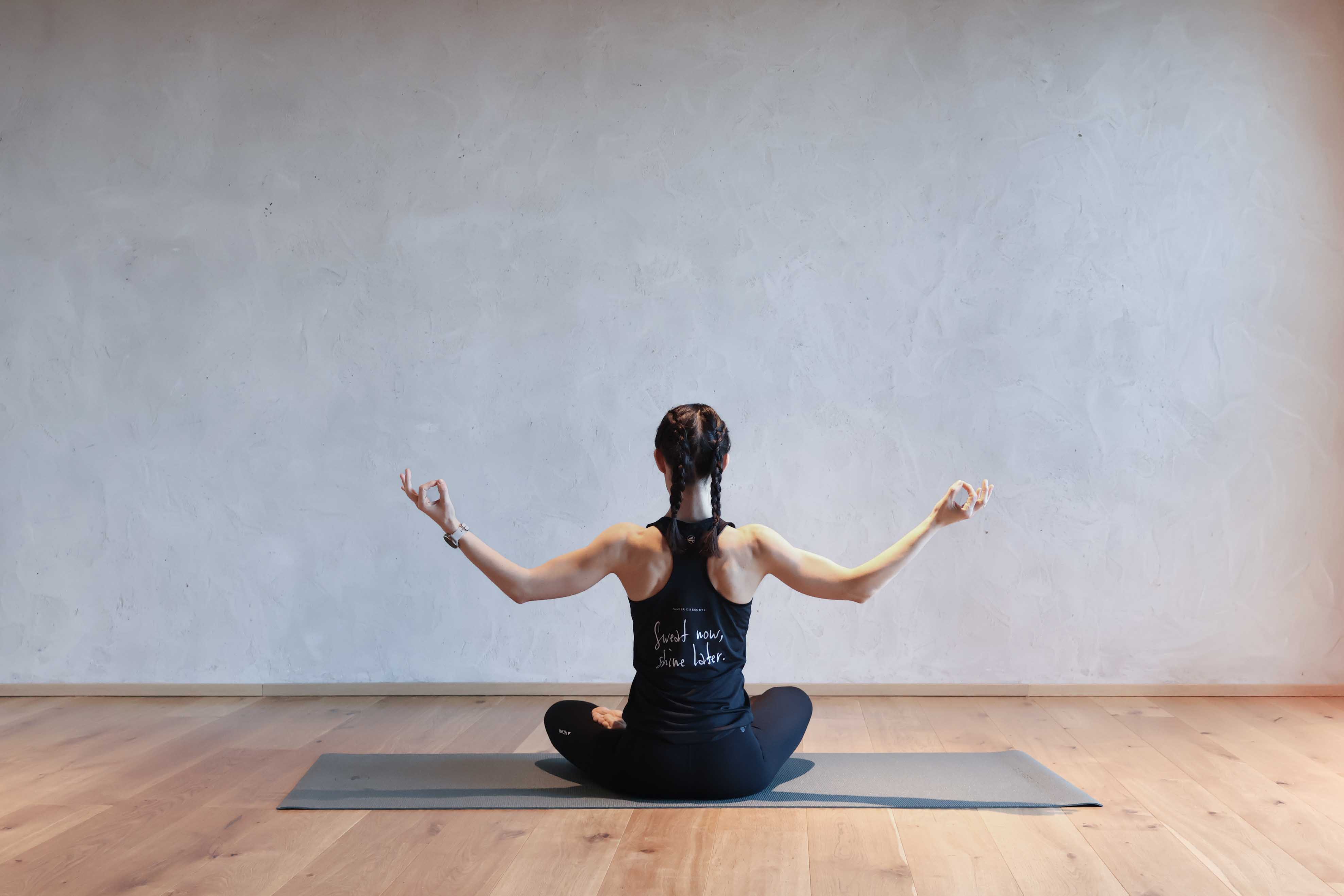 Frau meditiert in Yoga Pose im Active Studio eines Familux Resorts.