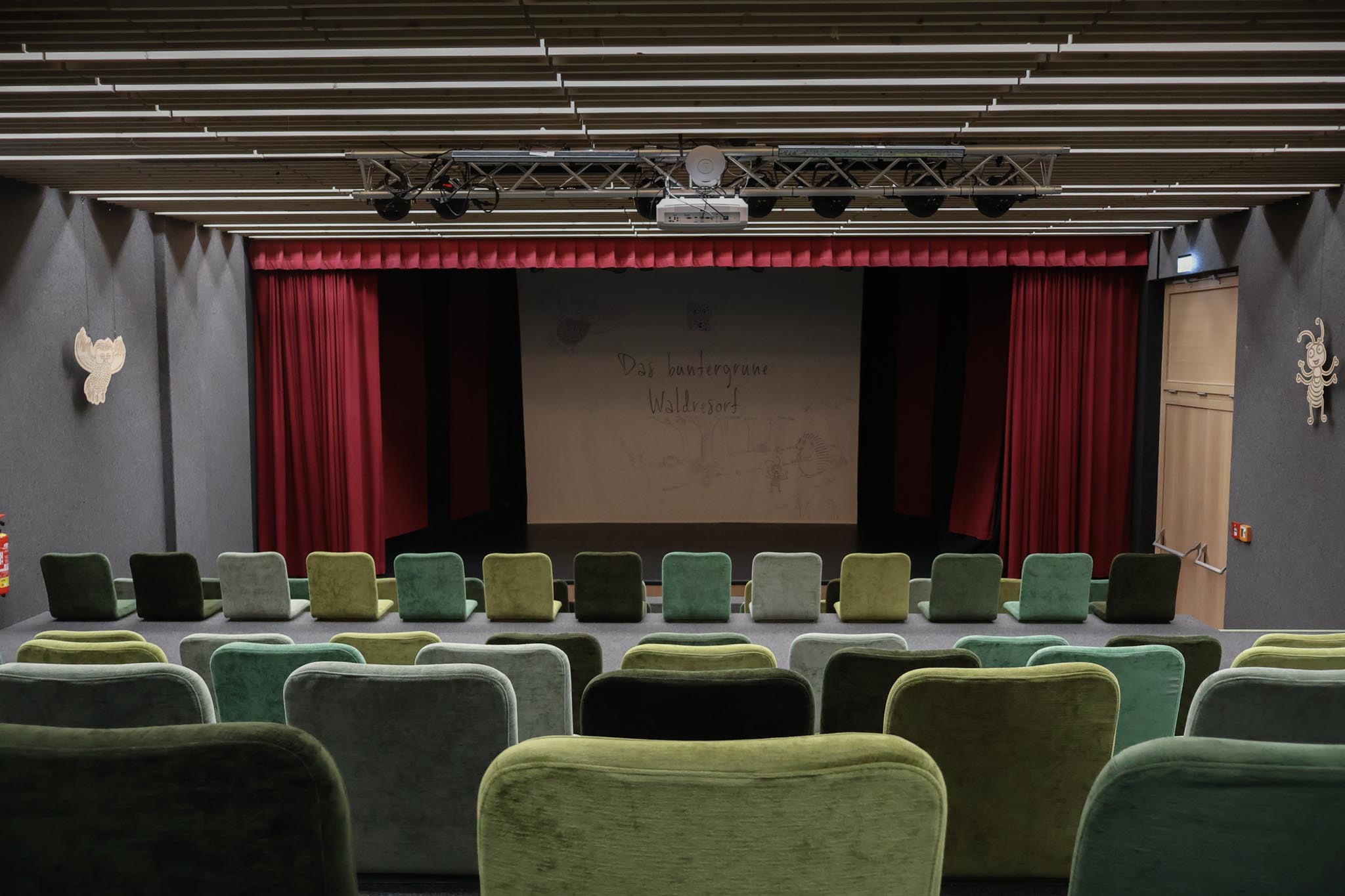 Theatre with green chairs and stage at The Grand Green – Familux Resort.