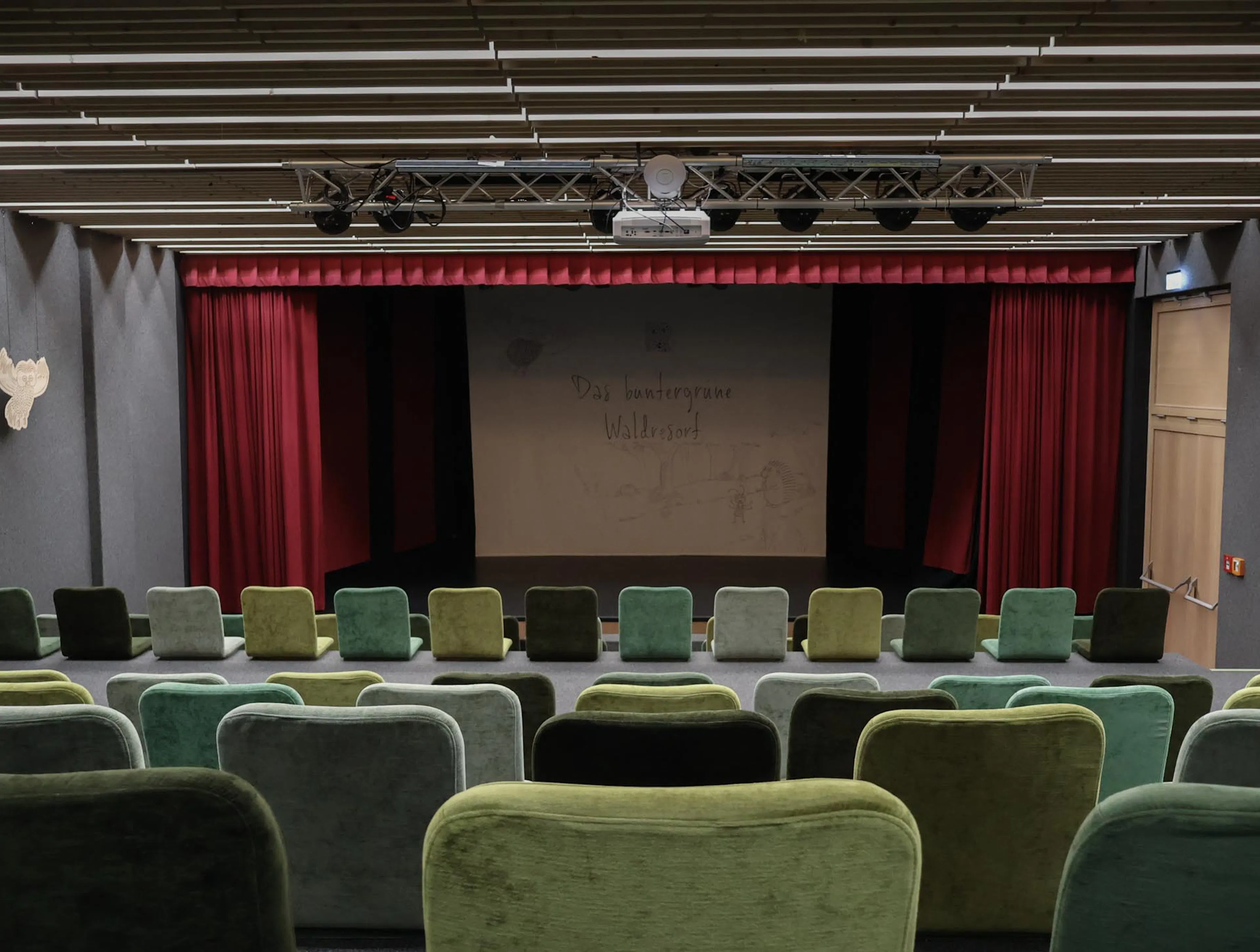 Theatre with green chairs and stage at The Grand Green – Familux Resort.