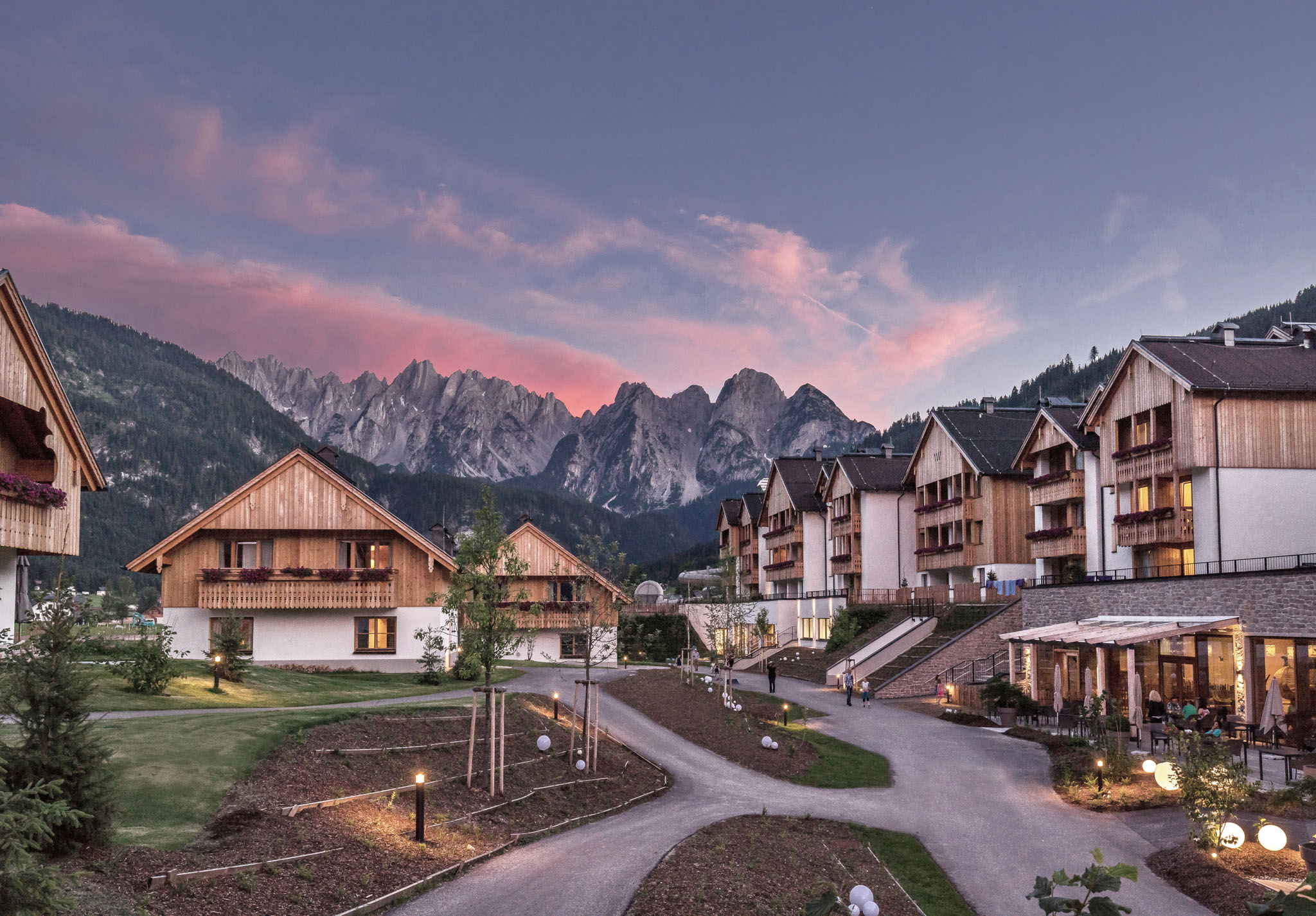 Dachsteinkönig - Familux Resort mit Hotel und Chalets und Blick auf die Berge im Sommer.