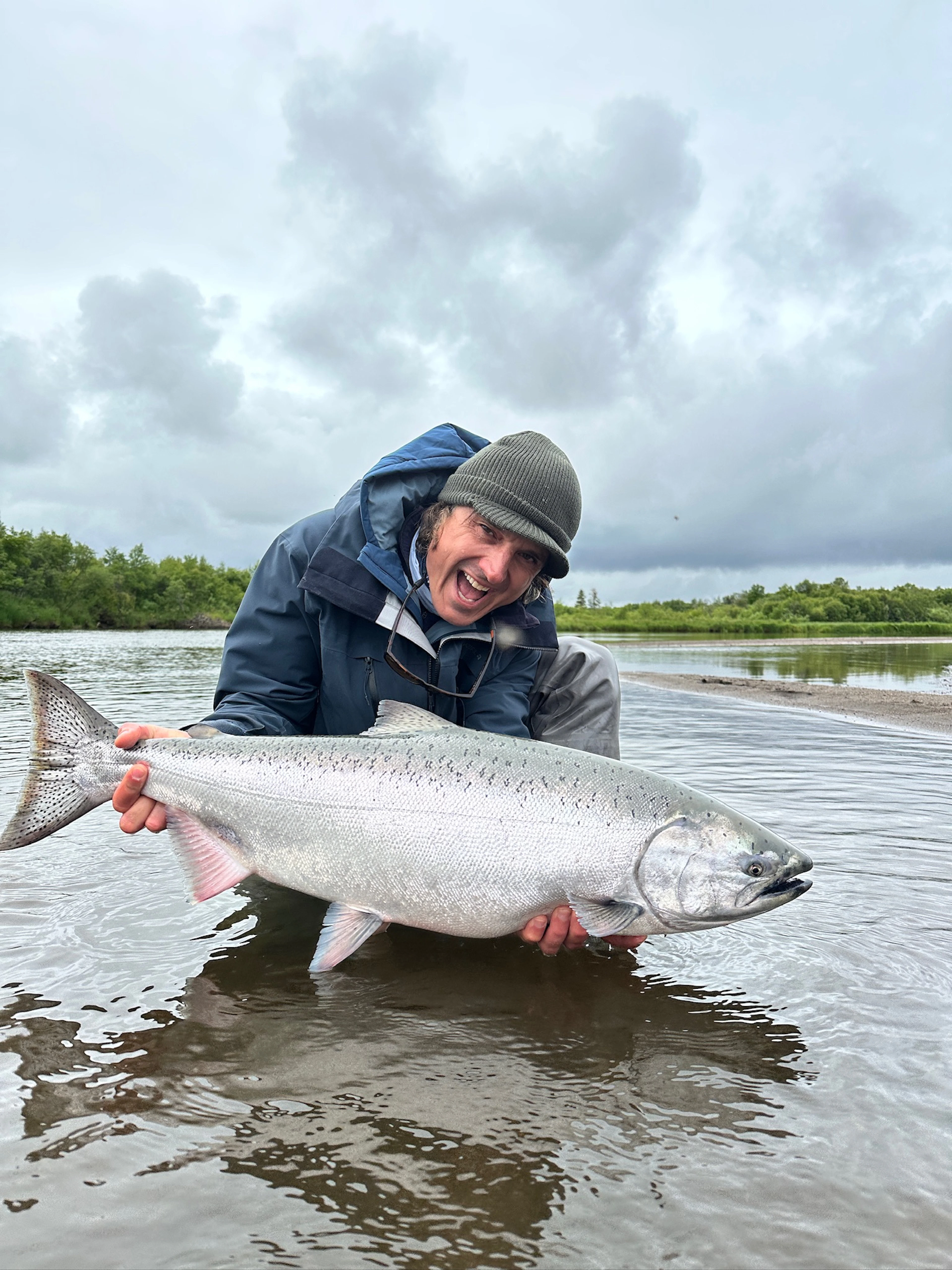 Angler holding king salmon  on the river at The Lodge at 58* North during peak Alaska fishing season