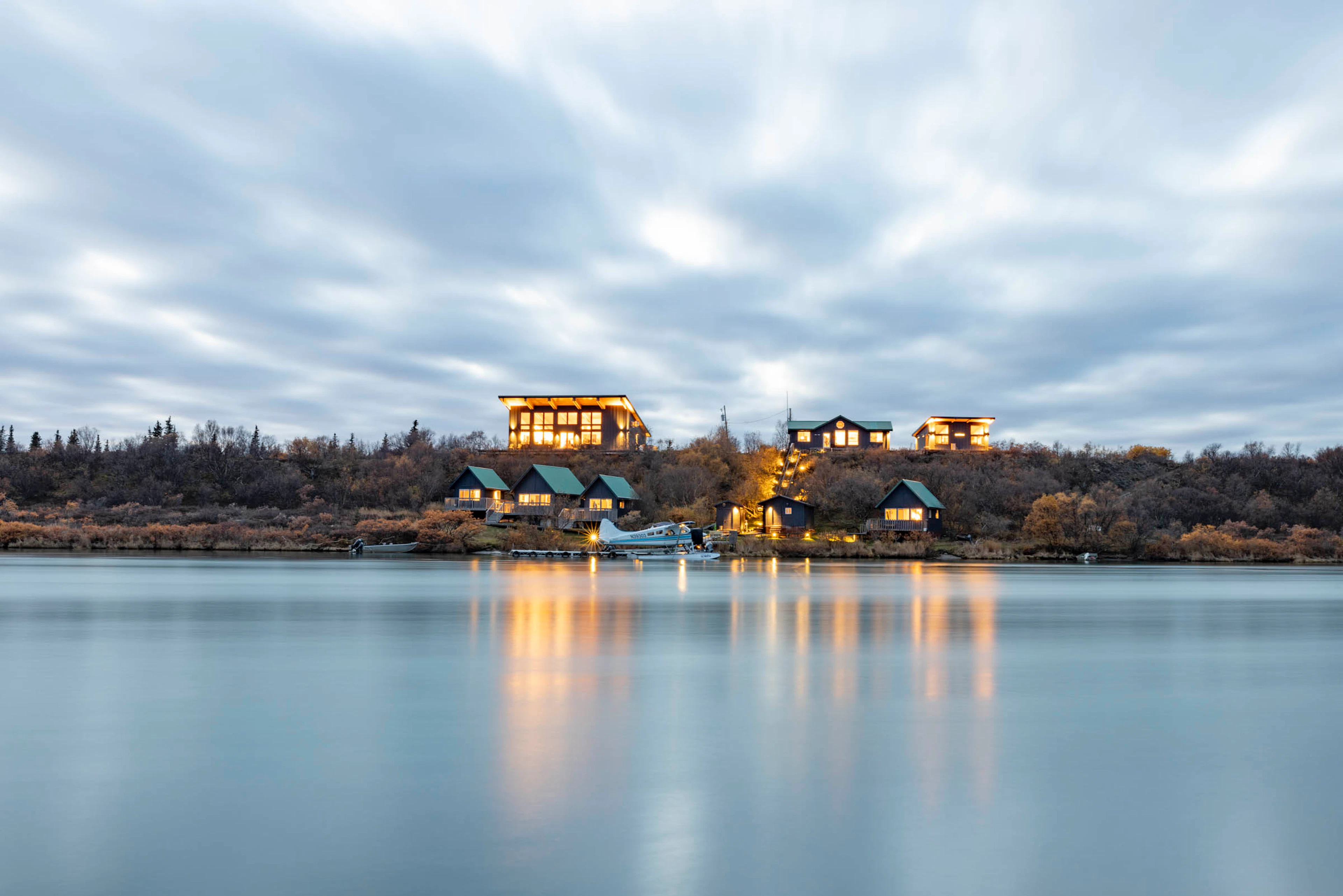 Luxury Alaska fishing lodge with waterfront cabins and floatplane during sunset