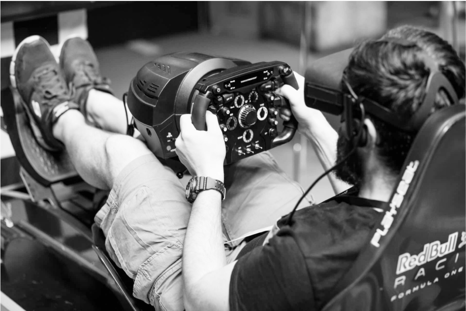 Een man zit in een VR race game met een VR bril op.