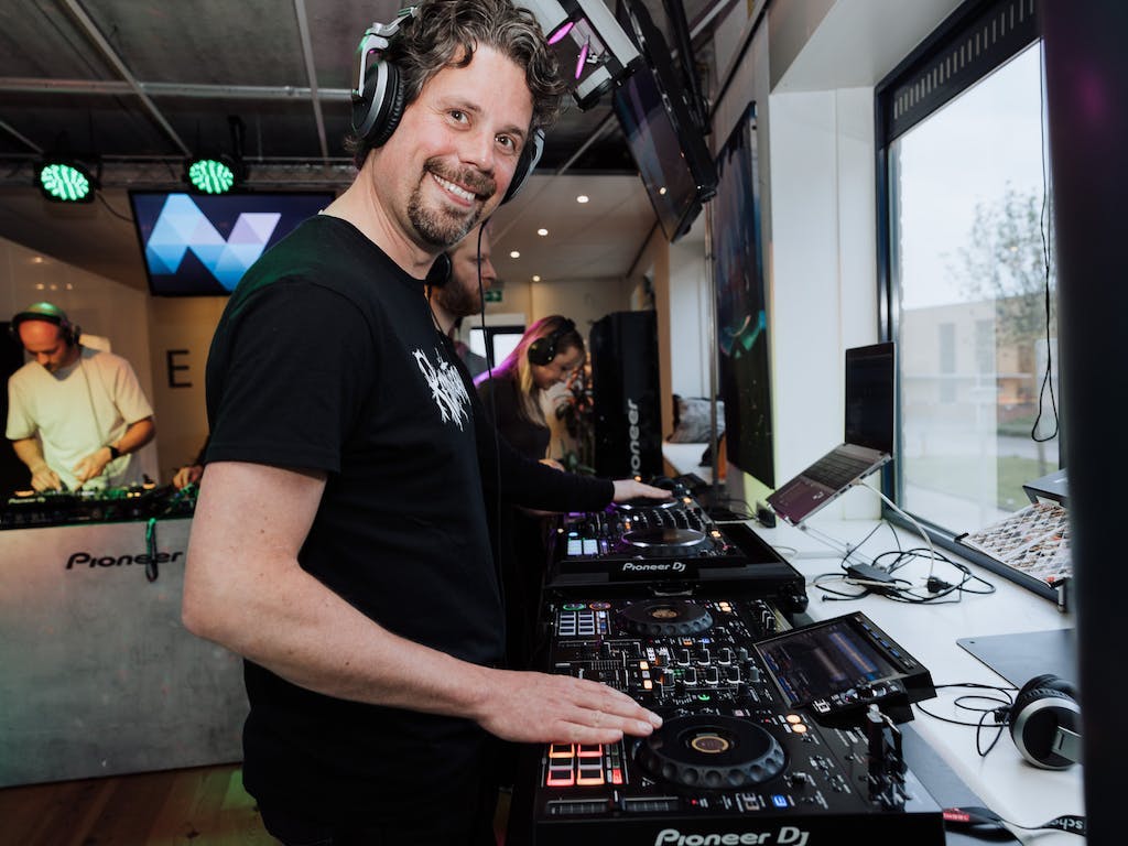 Een NextGenner lachend achter een draaitafel tijdens een The.NextGen DJ Event.