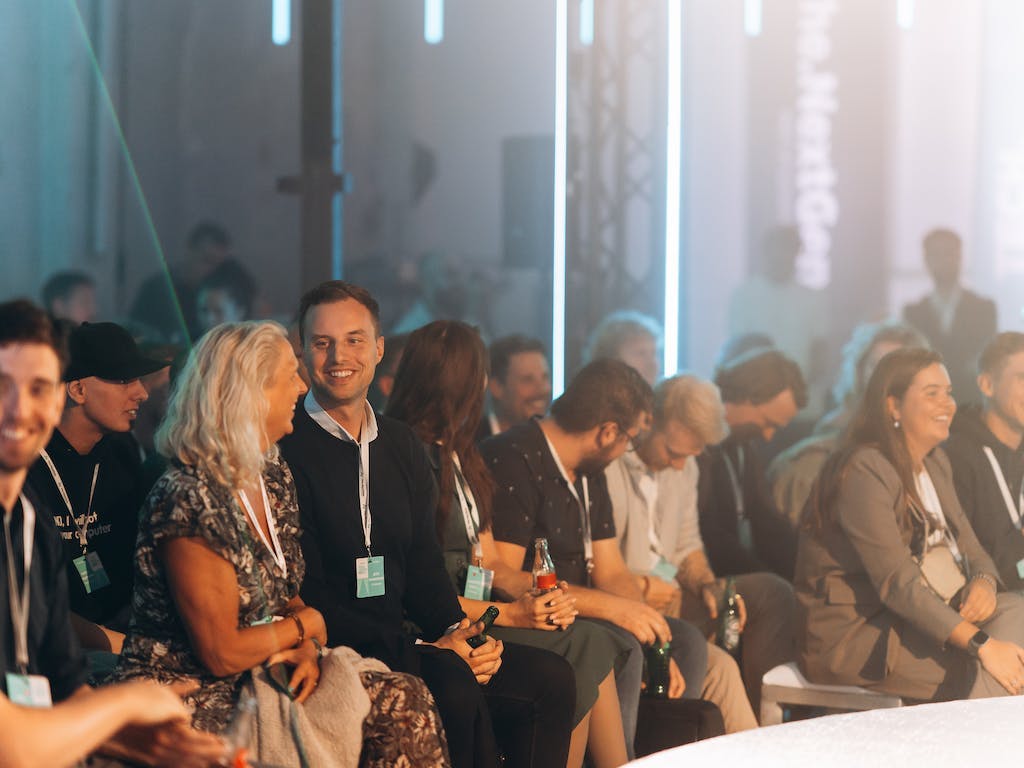 Volle zaal The.NextGen TechKnowFest 2023 met lachende IT-specialisten.