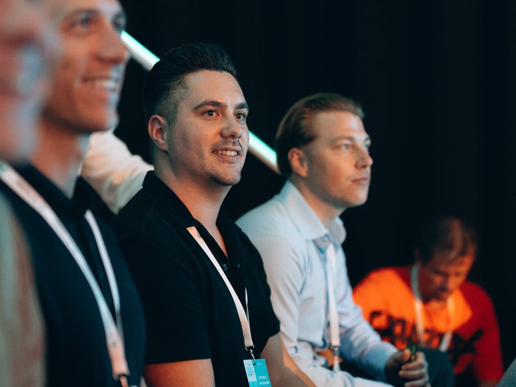 Drie geïnteresseerde NextGenners op de tribune tijdens The.NextGen TechKnowFest 2023.