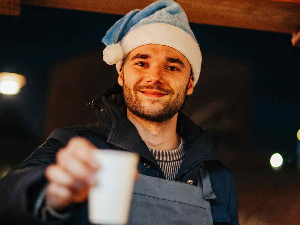 NextGen medewerker biedt een drankje in een papieren beker aan.