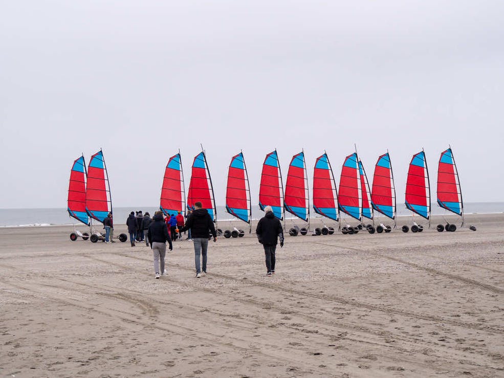 Een groep IT specialisten loopt op het strand richting een rij blokarts.