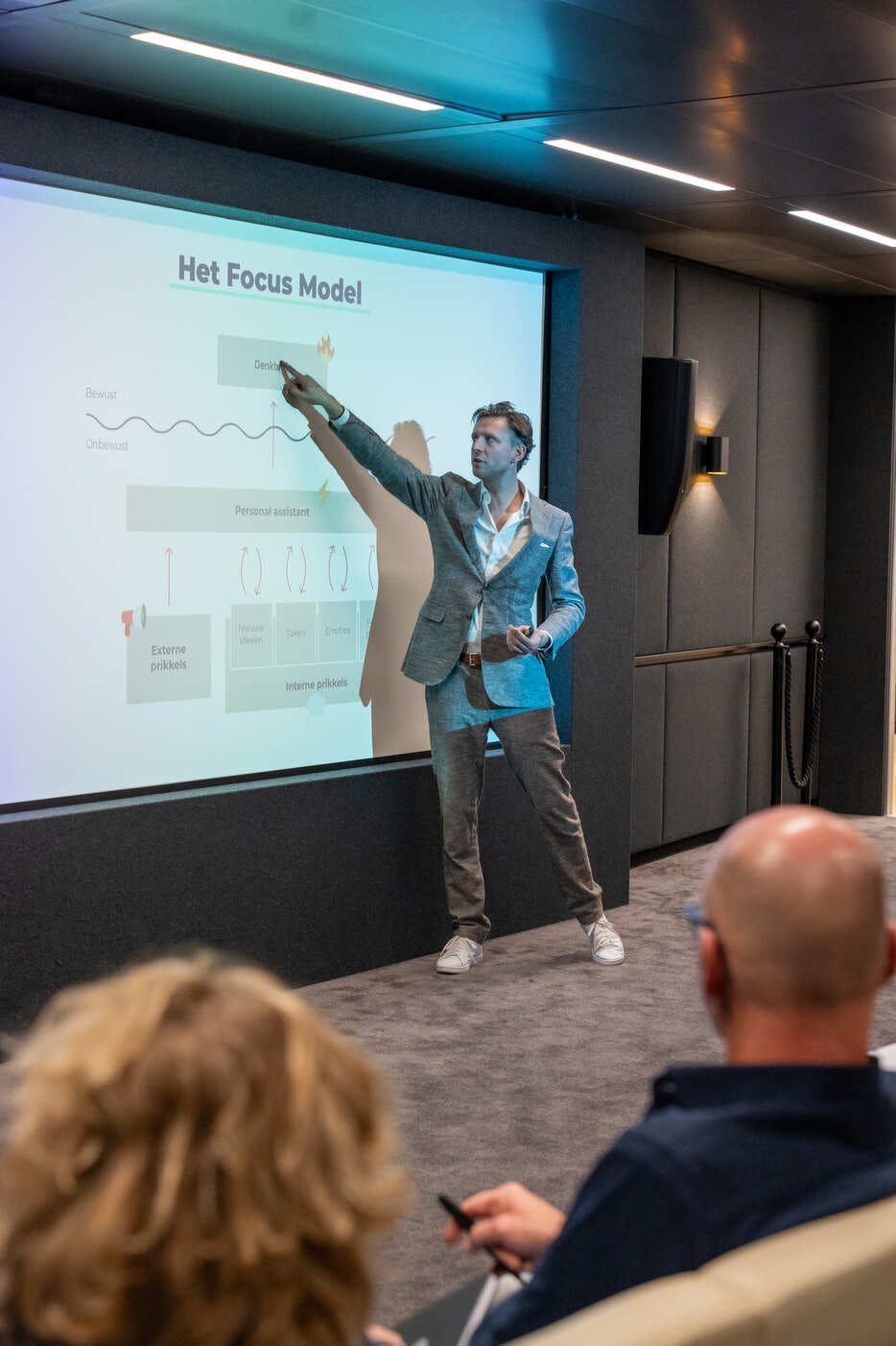 Focus expert Marc Tigchelaer staat voor een volle zaal van IT professionals en wijst naar een scherm.