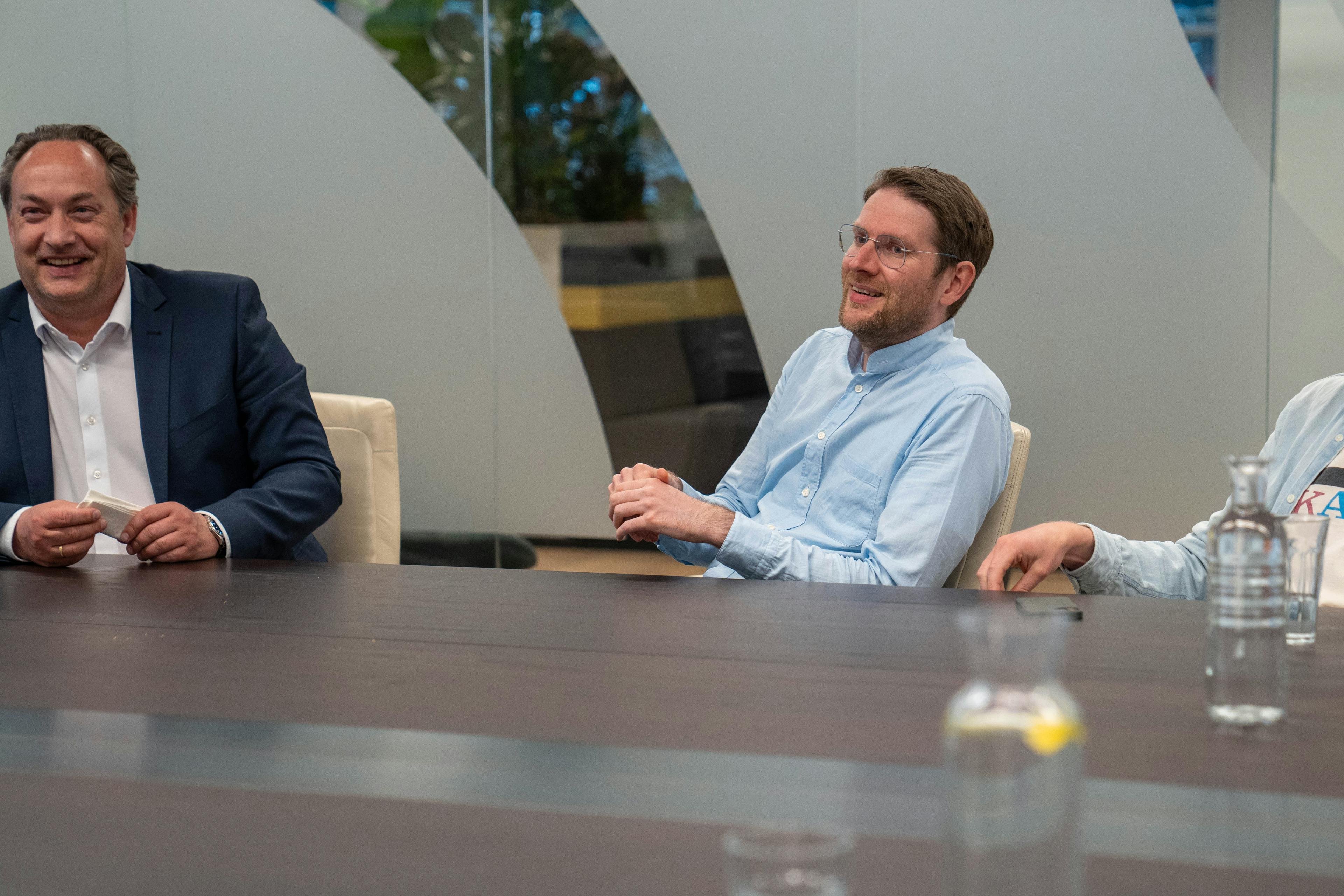 Jan Jaap glimlachend in een vergaderruimte op kantoor.