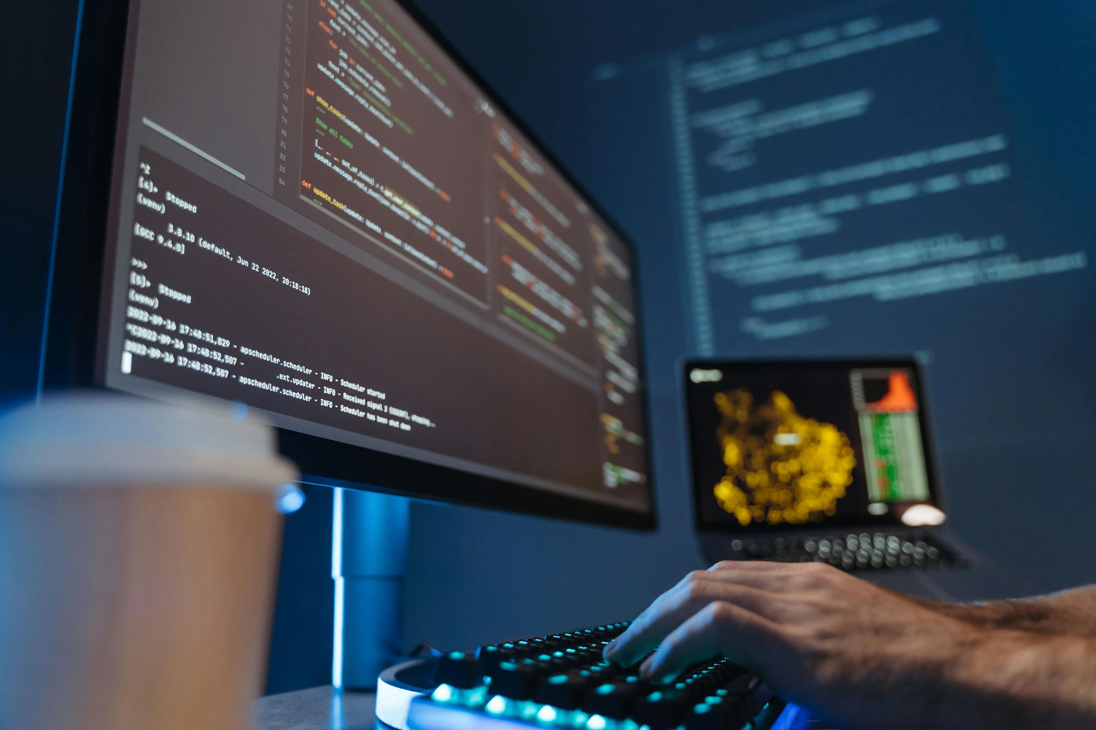 A screen with Java code. A coffee cup in the bottom left of the screen, and hands on a keyboard.
