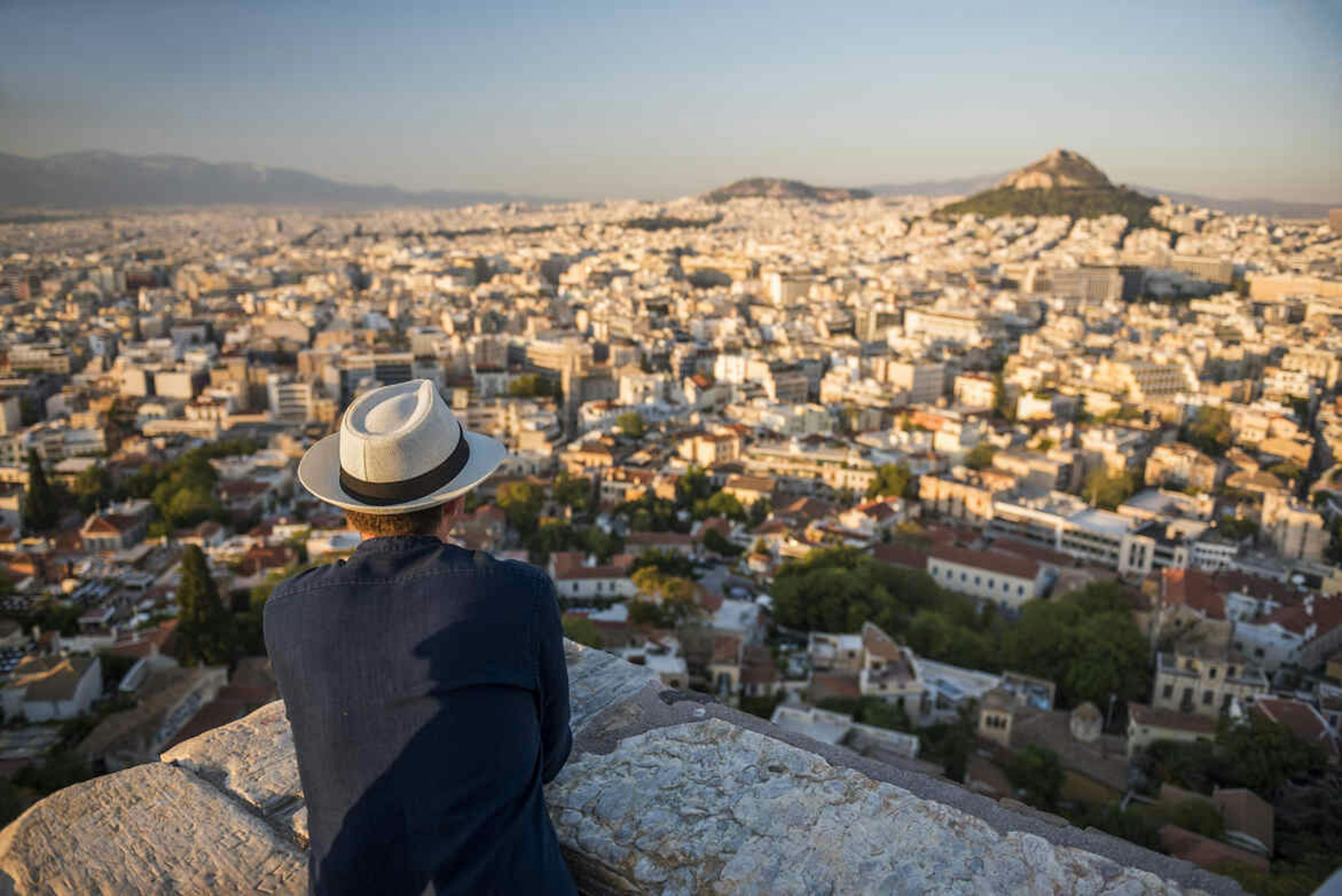 Man met hoed kijkt uit over uitzicht van stad Athene. 