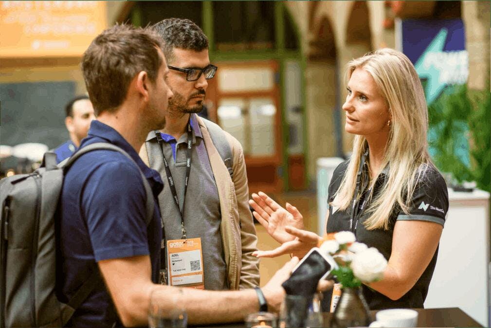 Een The.NextGen medewerker praat met twee IT talenten op de werkvloer.