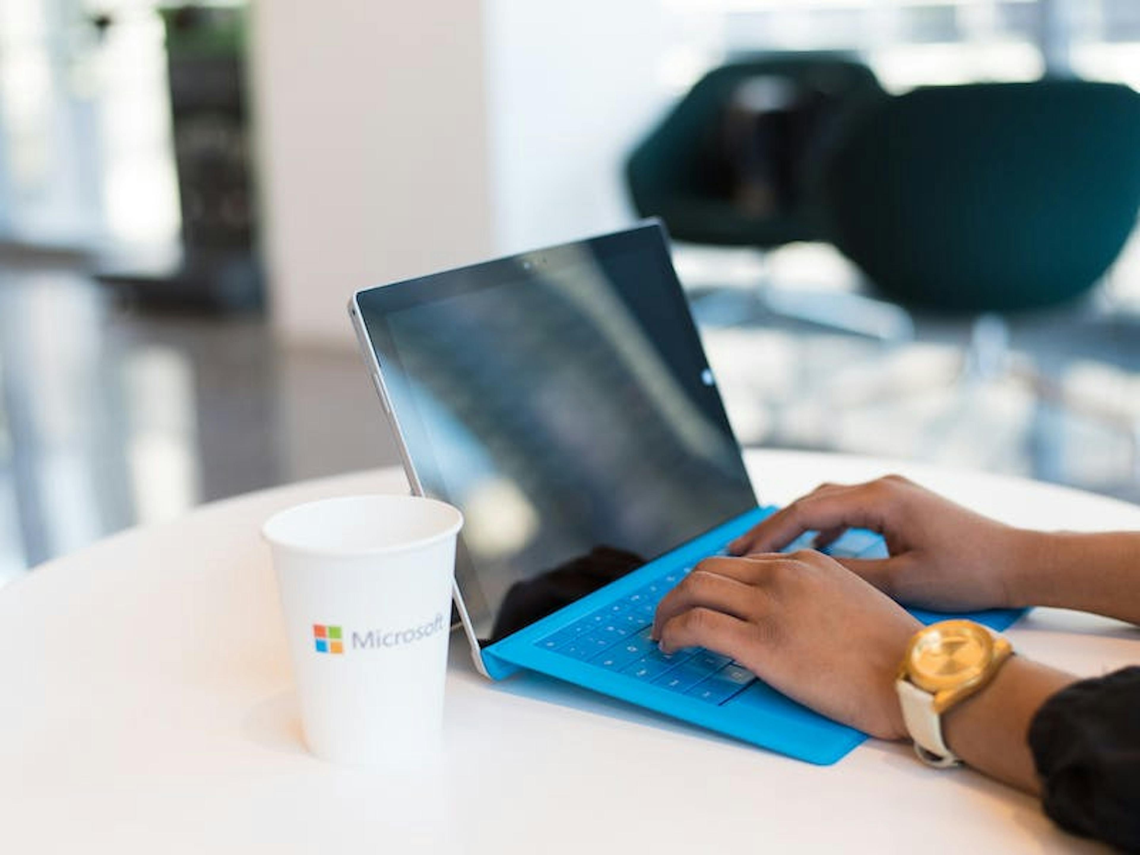 De handen van een vrouw rusten op het toetsenbord van een blauwe laptop. 