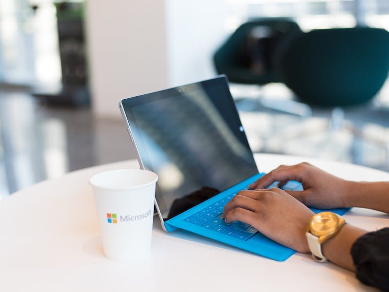 De handen van een vrouw rusten op het toetsenbord van een blauwe laptop.