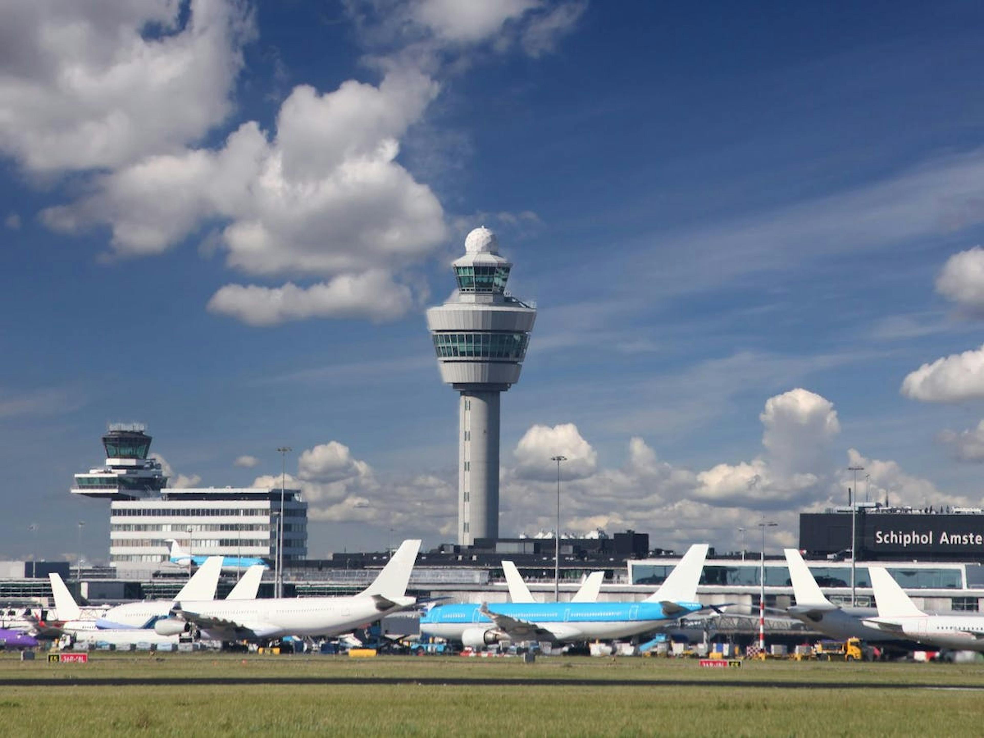 Schiphol toren en geparkeerde vliegtuigen eronder. 