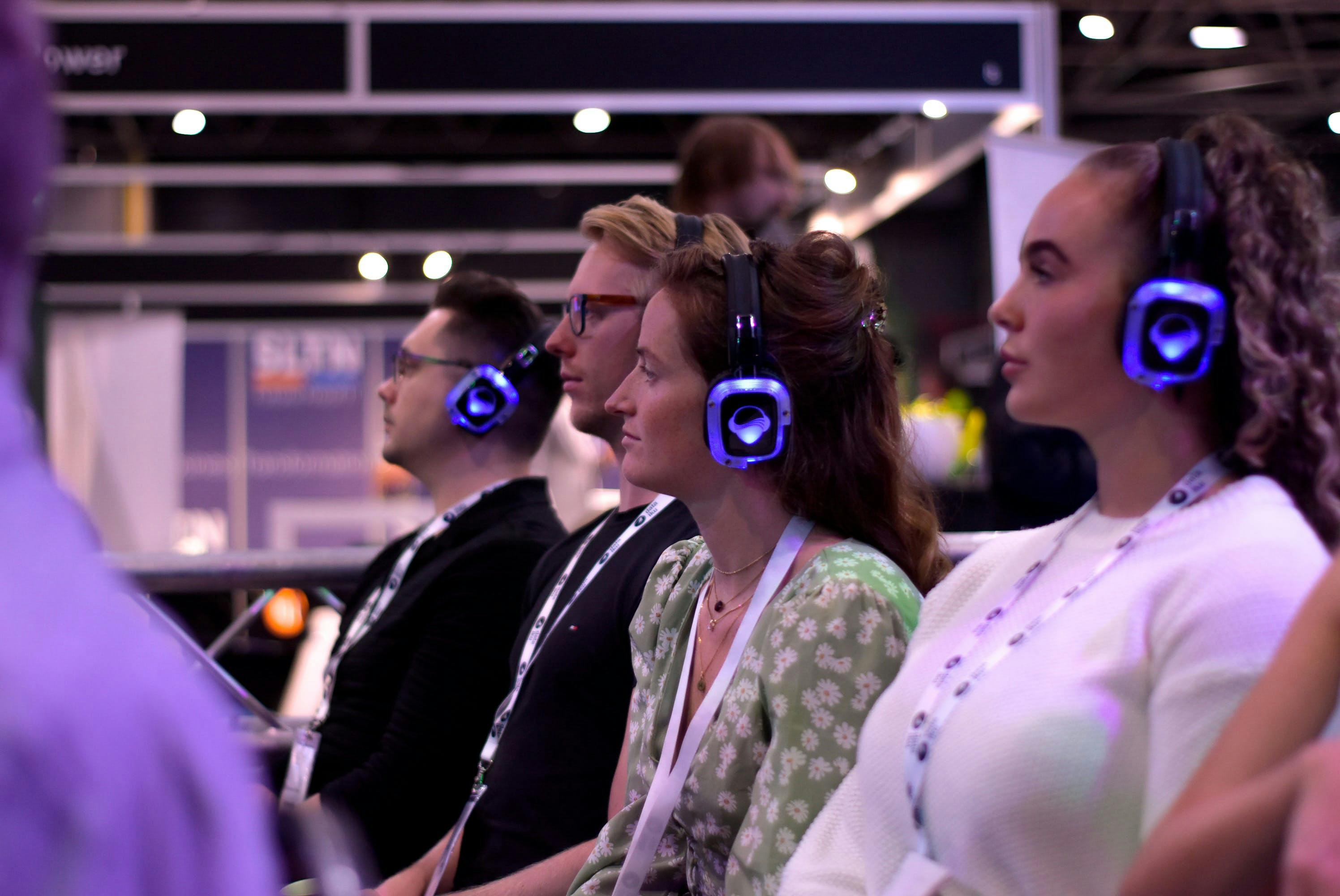 Vier NextGen medewerkers zitten aandachtig te luisteren met koptelefoon op tijdens een speciale presentatie op de Big Data Expo.