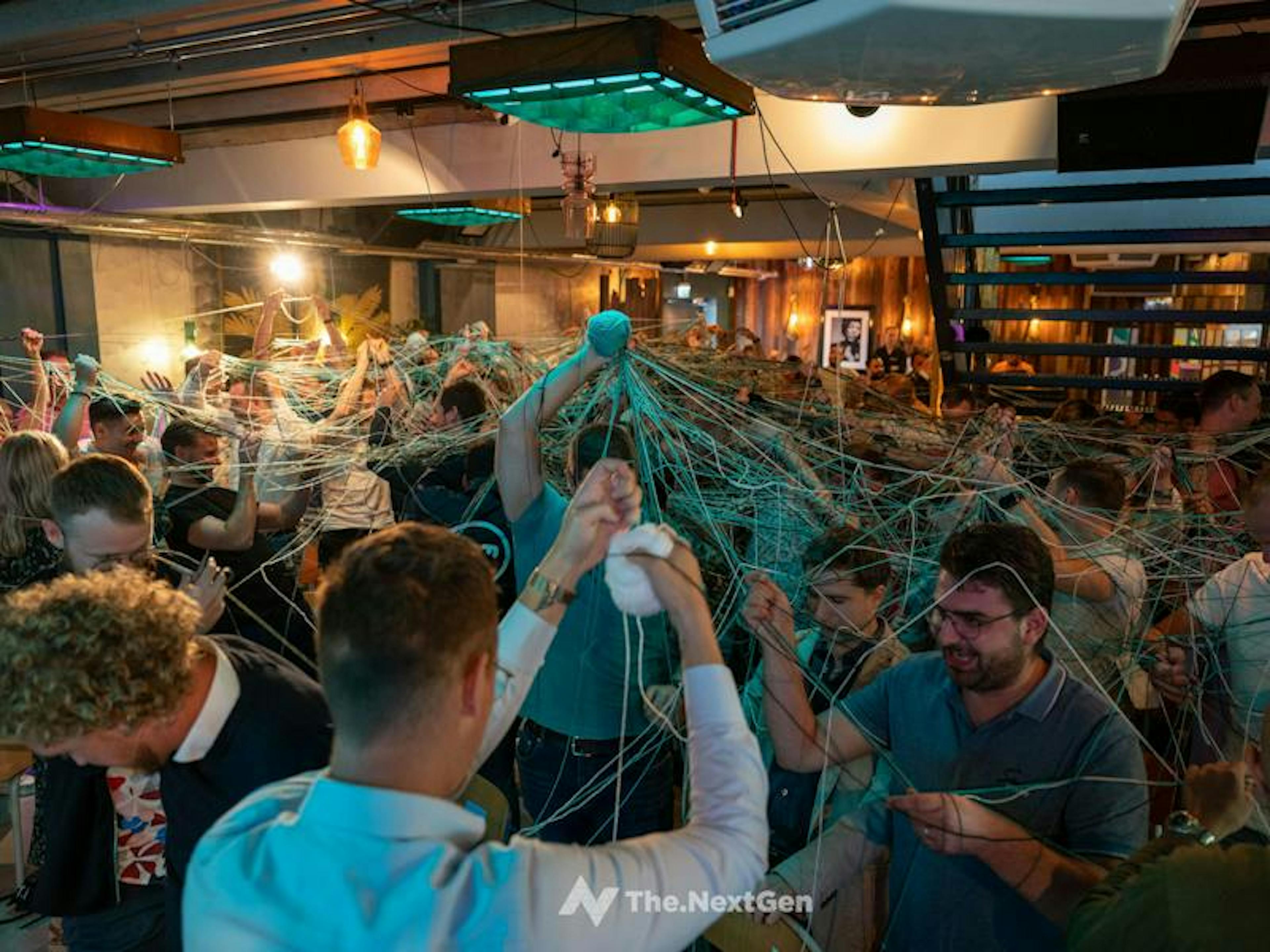 Een zaal vol NextGenners doet mee aan een teambuilding oefening.