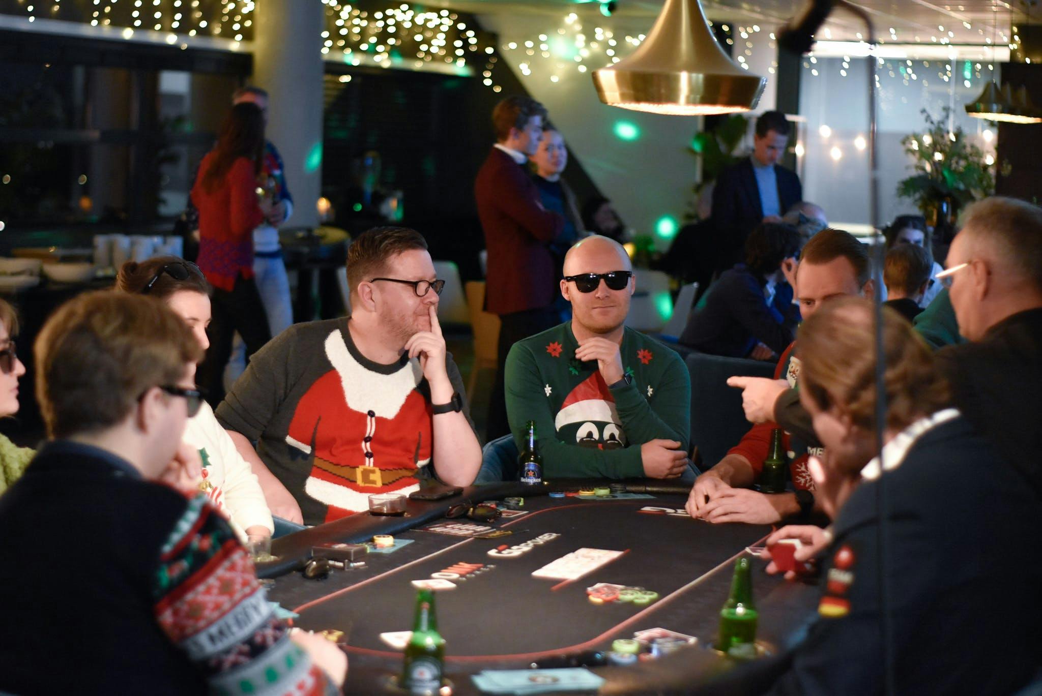 Een groep NextGenners speelt poken in ugly christmas sweaters.