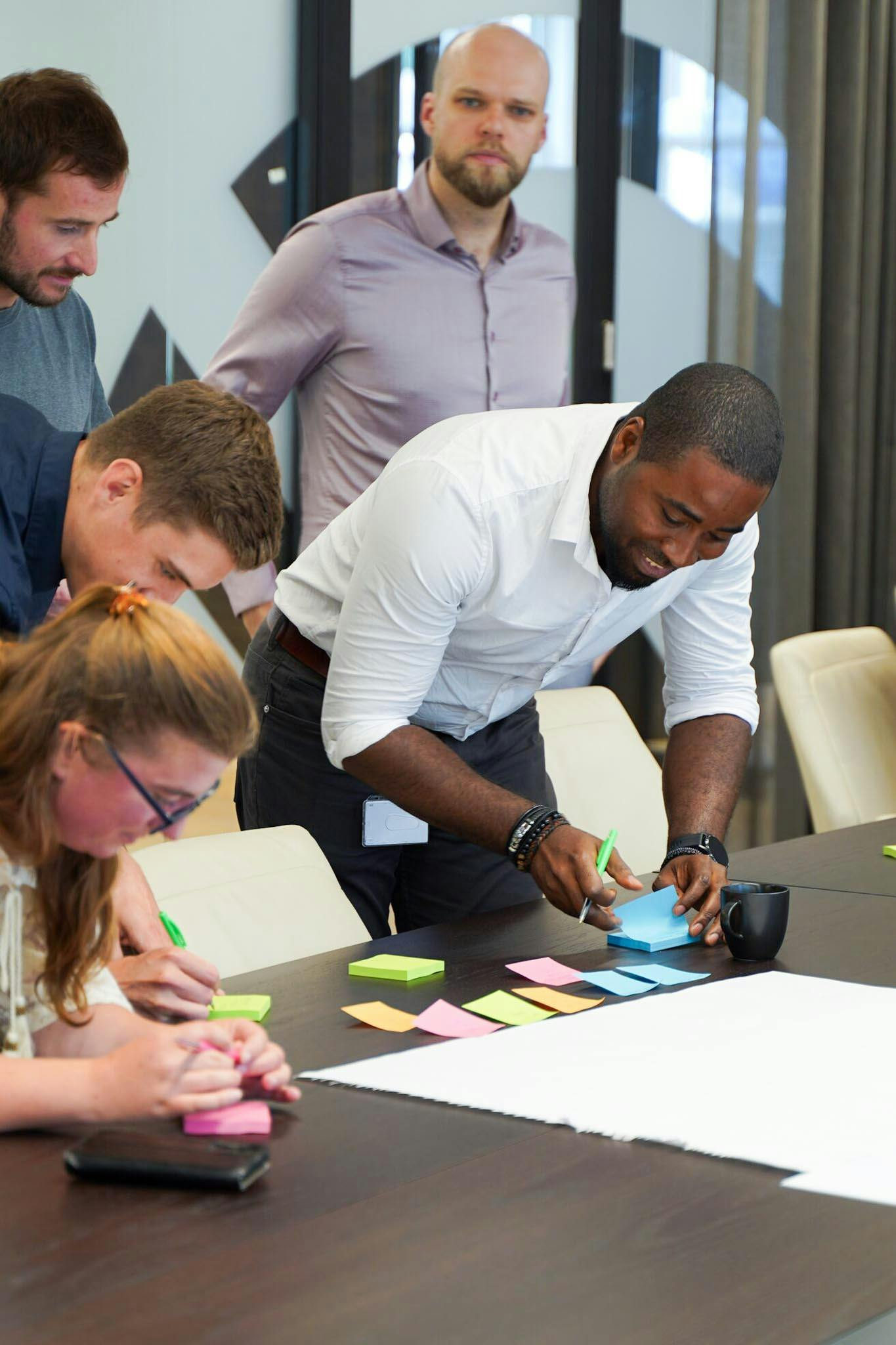 NextGenner Dja lachend terwijl hij een post-it note plakt in een groep van andere NextGenners.