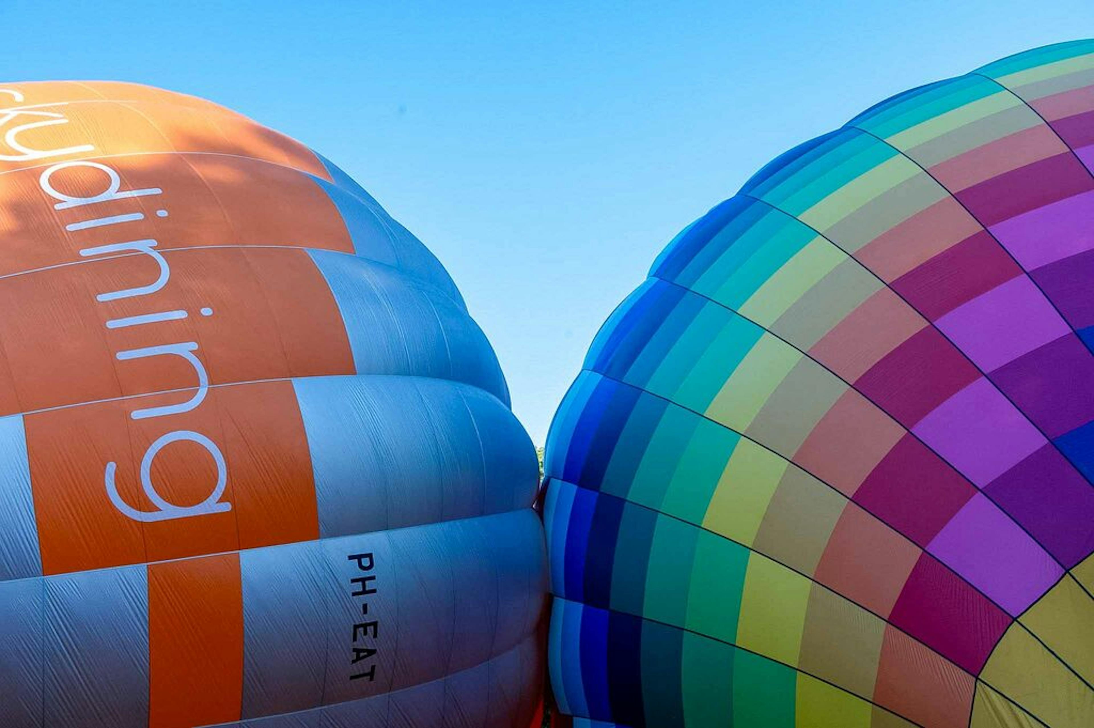 Twee luchtballonnen worden langzaam opgeblazen terwijl de toppen tegen elkaar liggen