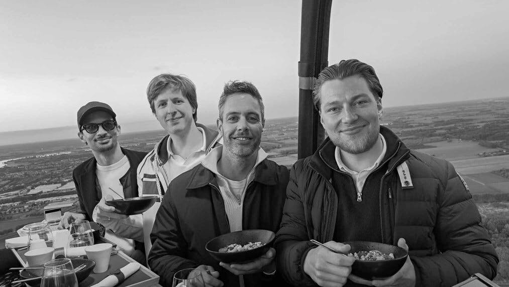 Rob Varekamp, Jasper Bolland en twee NextGenners (IT-specialisten) staan met een hapje in een luchtballon.