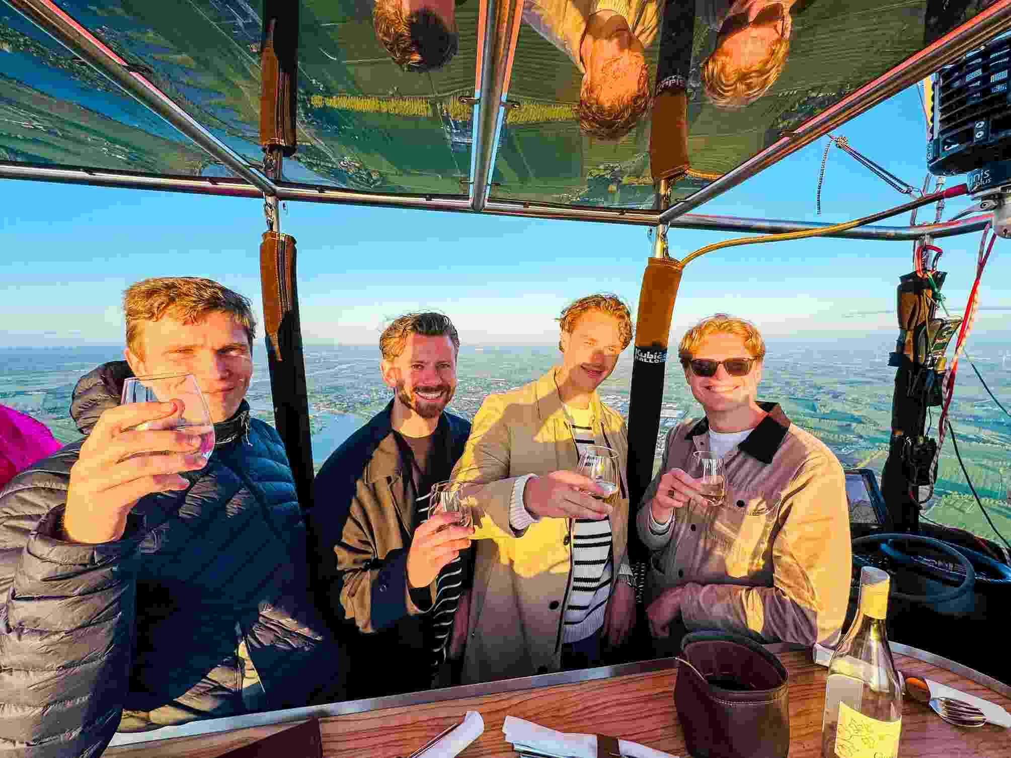 Raico van Elsen, Koen Dekker en twee The.NextGen IT specialisten staan met een drankje in een luchtballon.