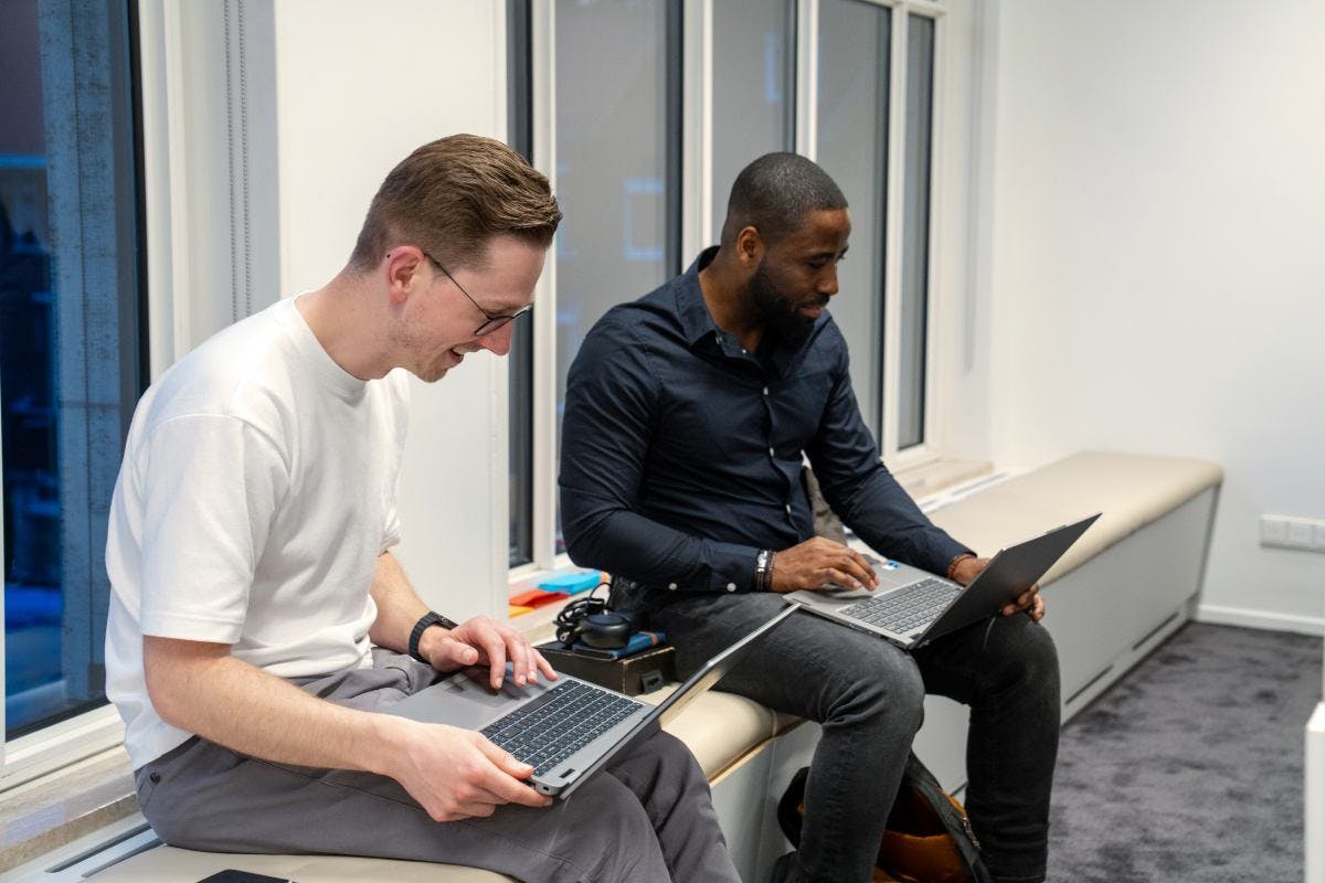 Twee it developers zijn lachend aan het coderen.