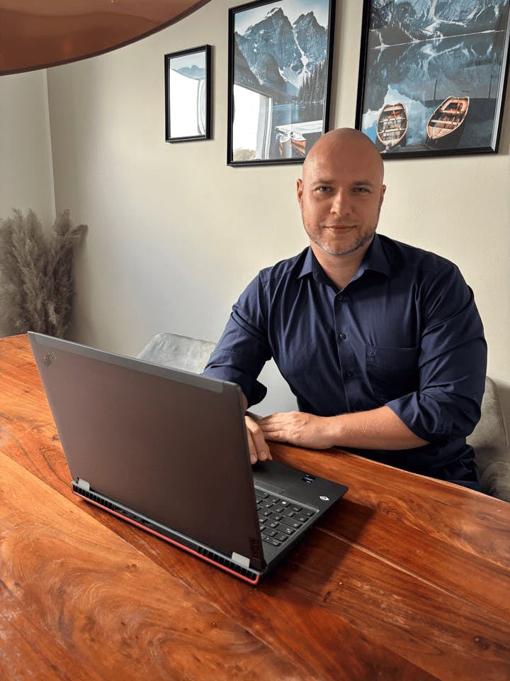 NextGenner Daniel sitzt in einem Büro hinter seinem Schreibtisch.