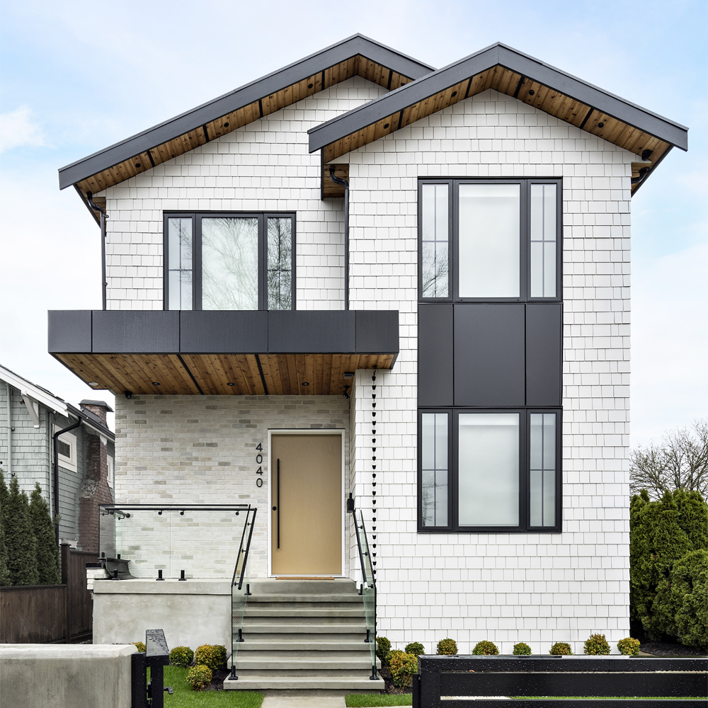 A modern white multiplex home with black trim and balcony.