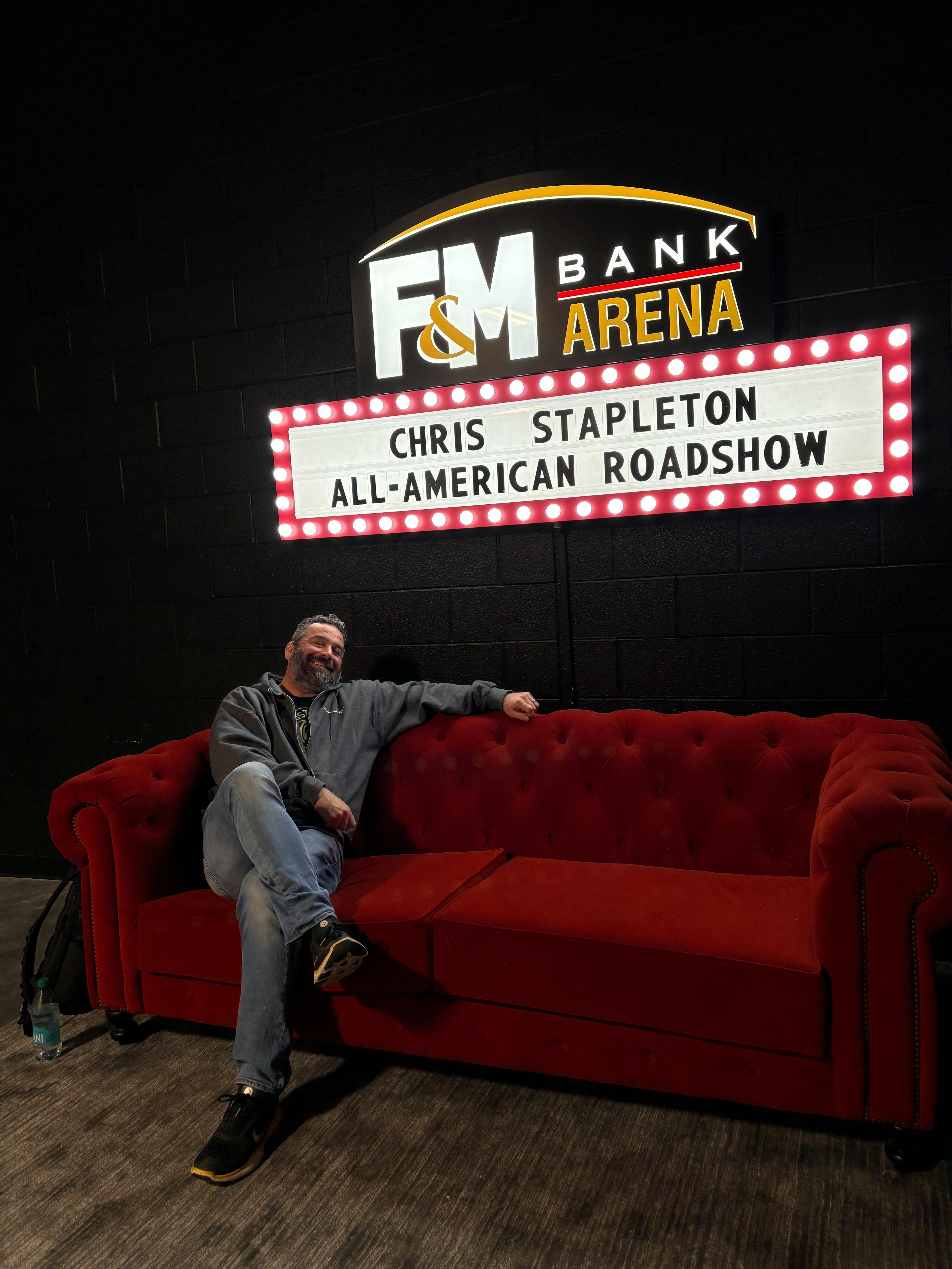 Tony Caperole Sitting Under "Welcome" Sign