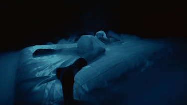 Suffocating visual cut from clip. A woman lying on a bed.