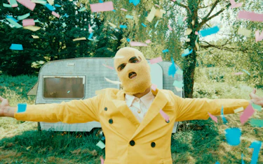 A yellow man raising his arms with confetti falling on him