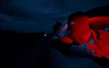 A red man looking by a car's window opened