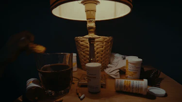 Image of a night table with a lamp and medication