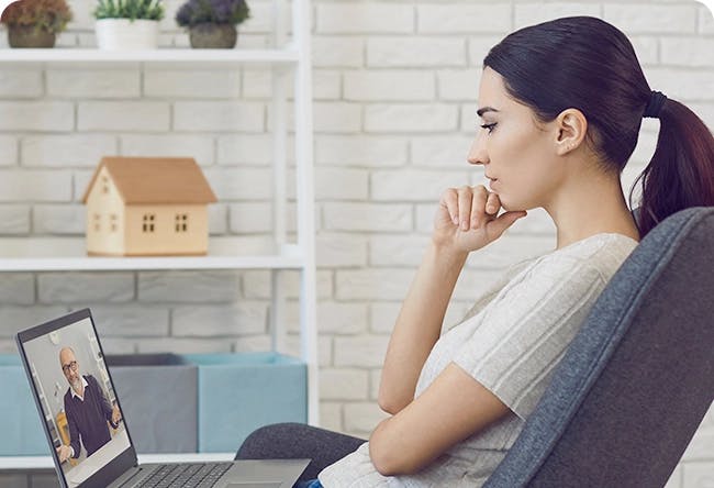 Person sitting in chair watching a video on their laptop