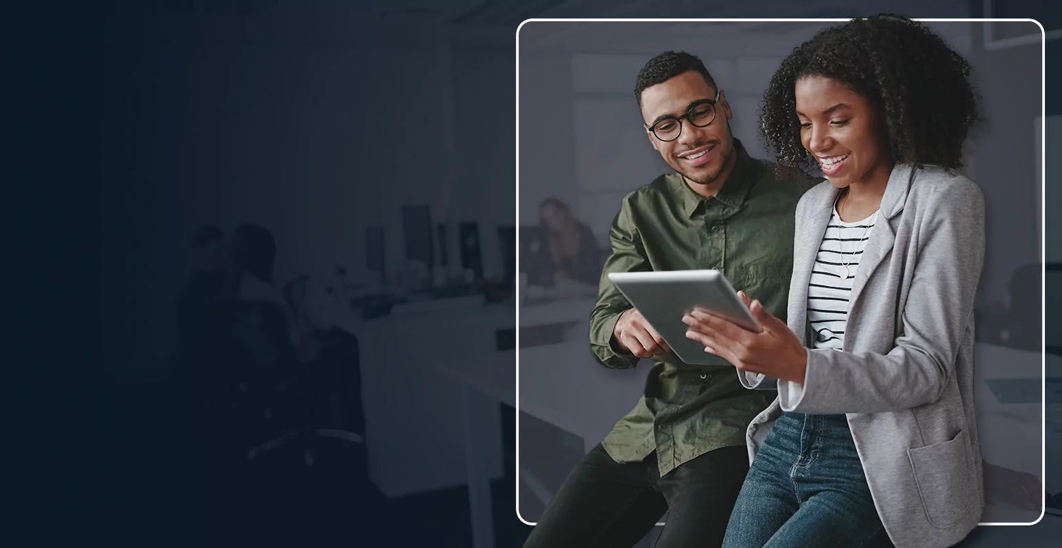 Two people smiling while looking at a tablet