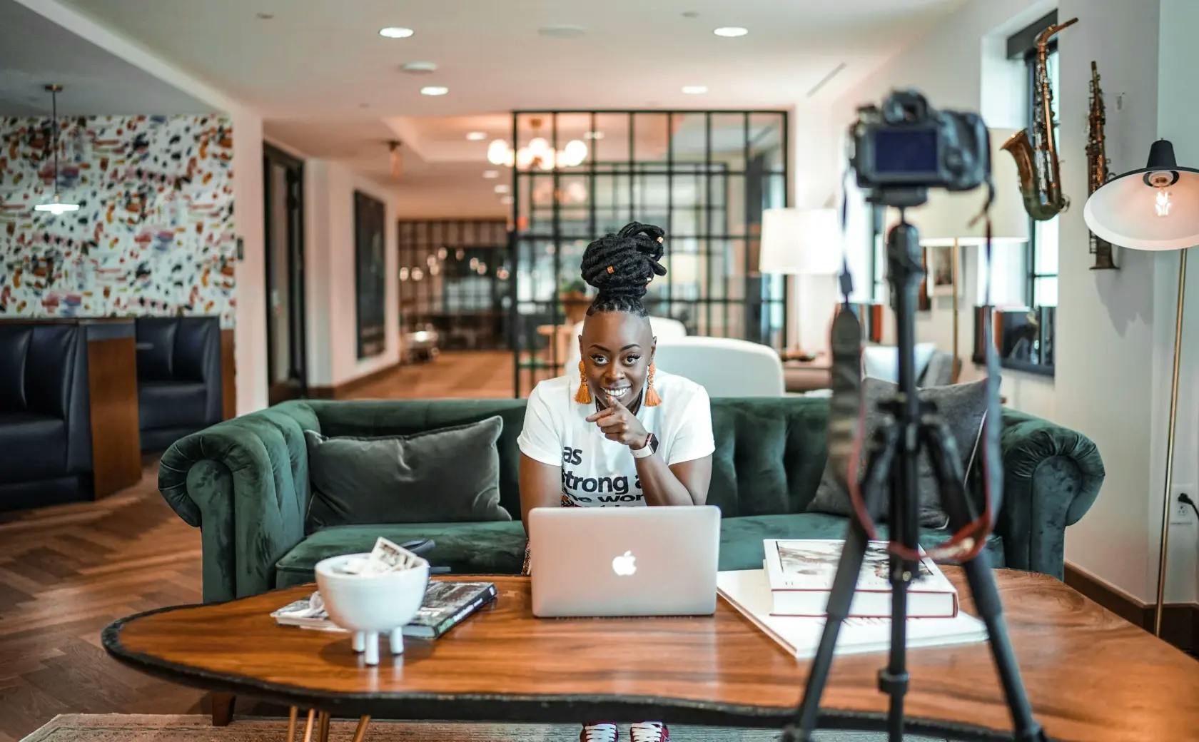 Woman sitting on couch smiling while being recorded