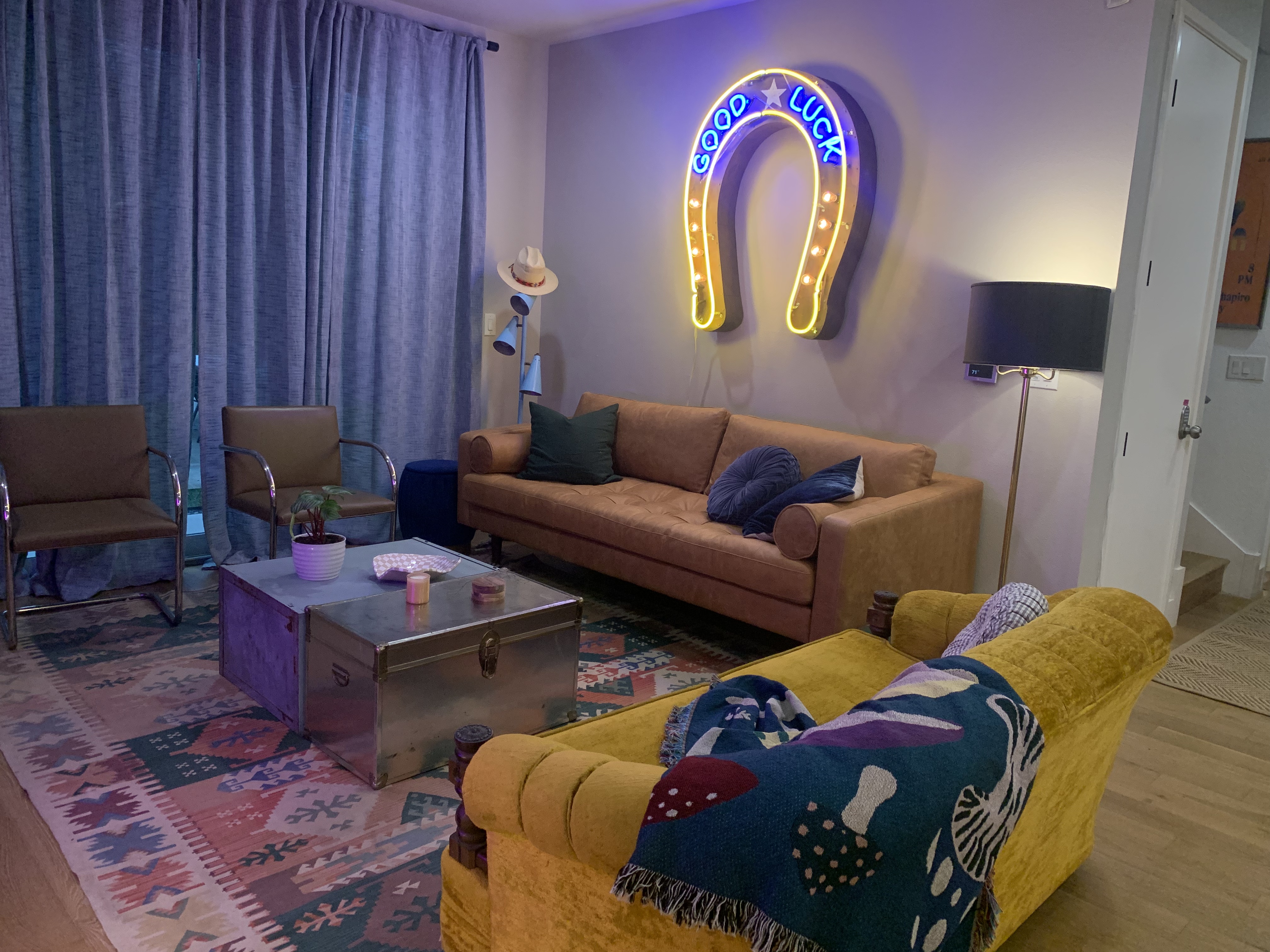 Two couches and chairs sit around a coffee table with a neon horseshoe with the text "Good luck" on the wall